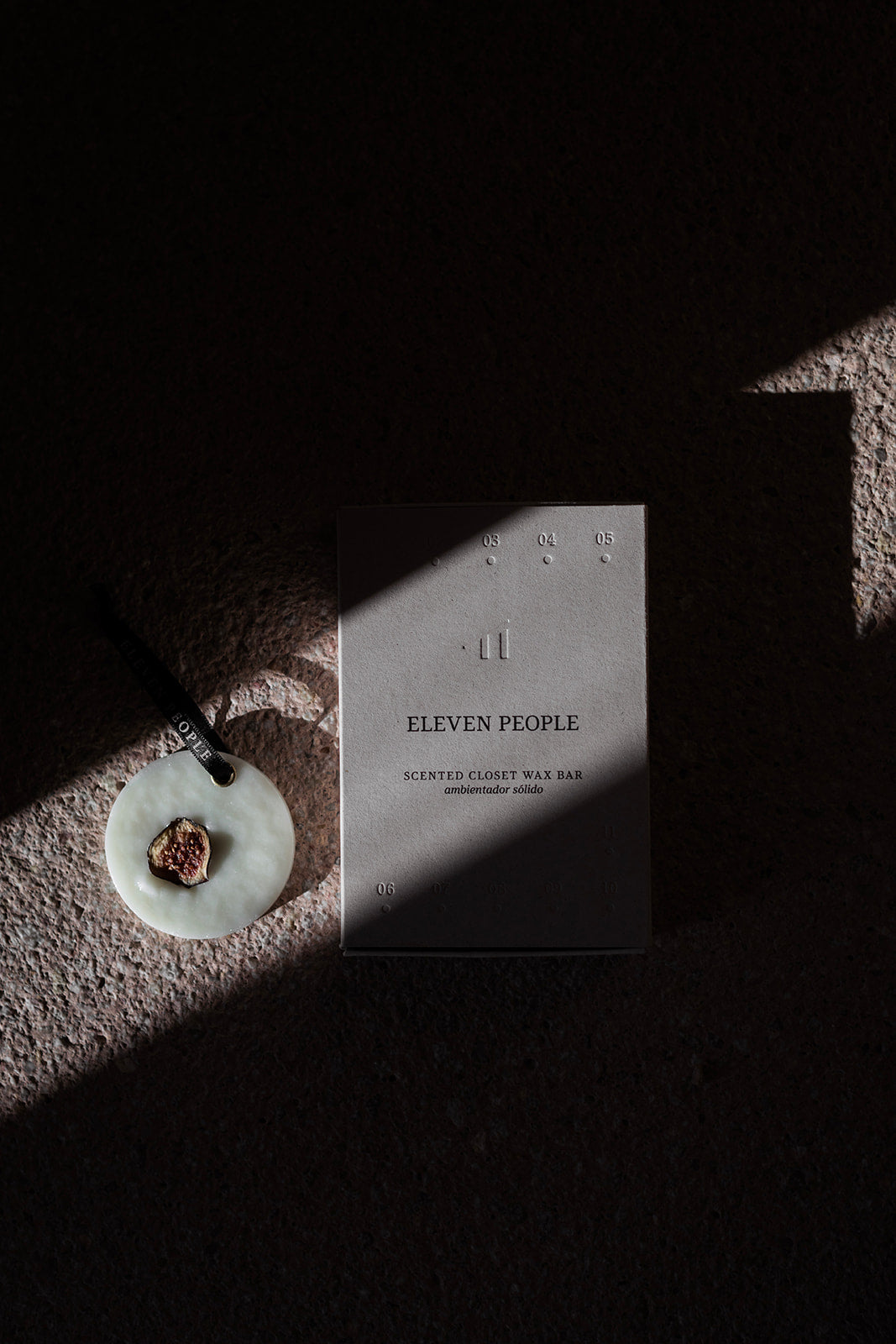 scented wax bar with a pendant next to a card titled 'Eleven People' on a textured surface.