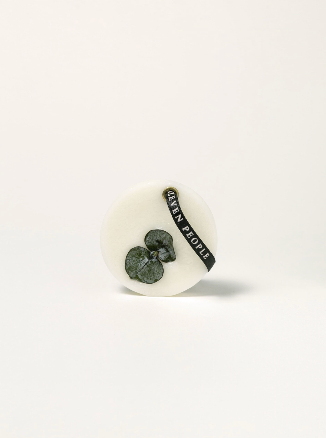 Round ceramic item with a green leaf design and black text on a white background