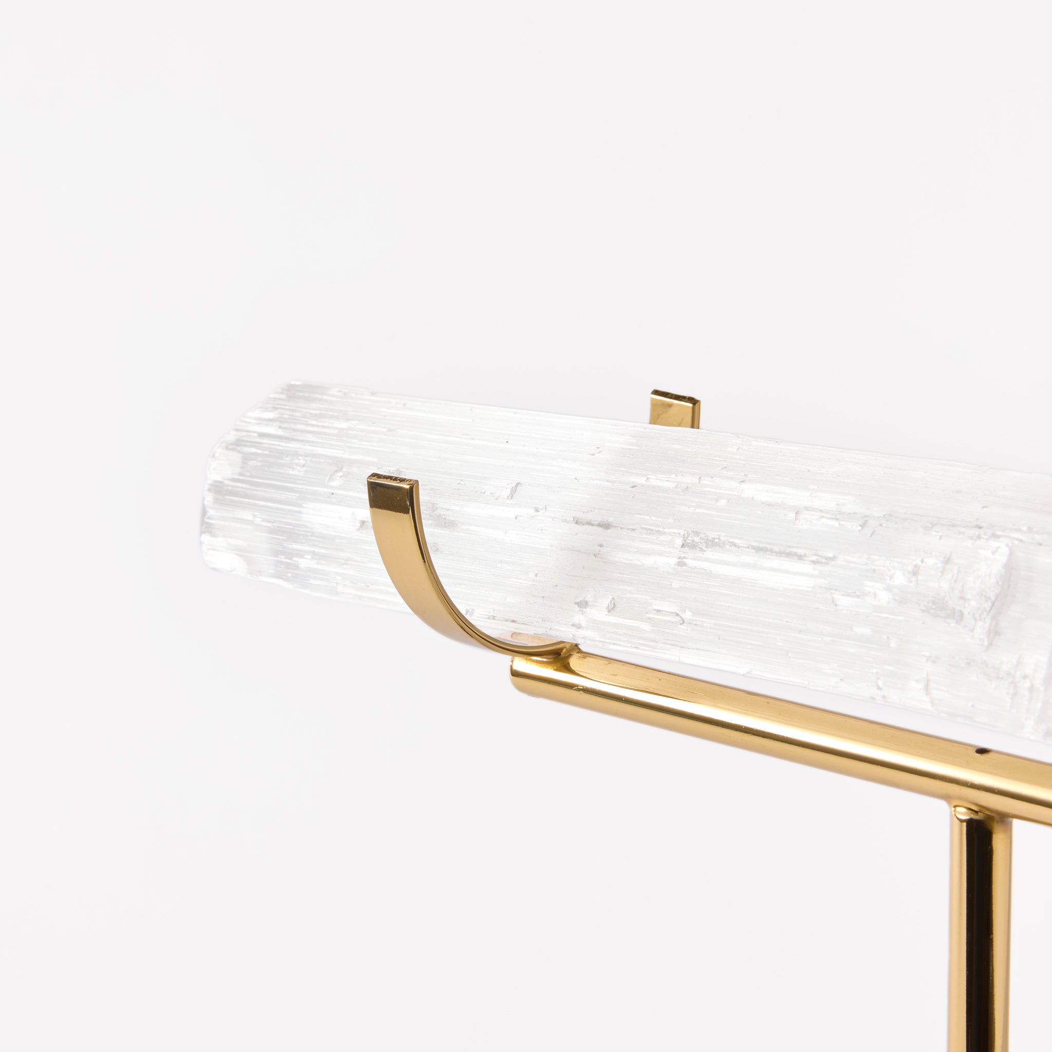 Decorative shelf with gold metal and clear glass design on a white background