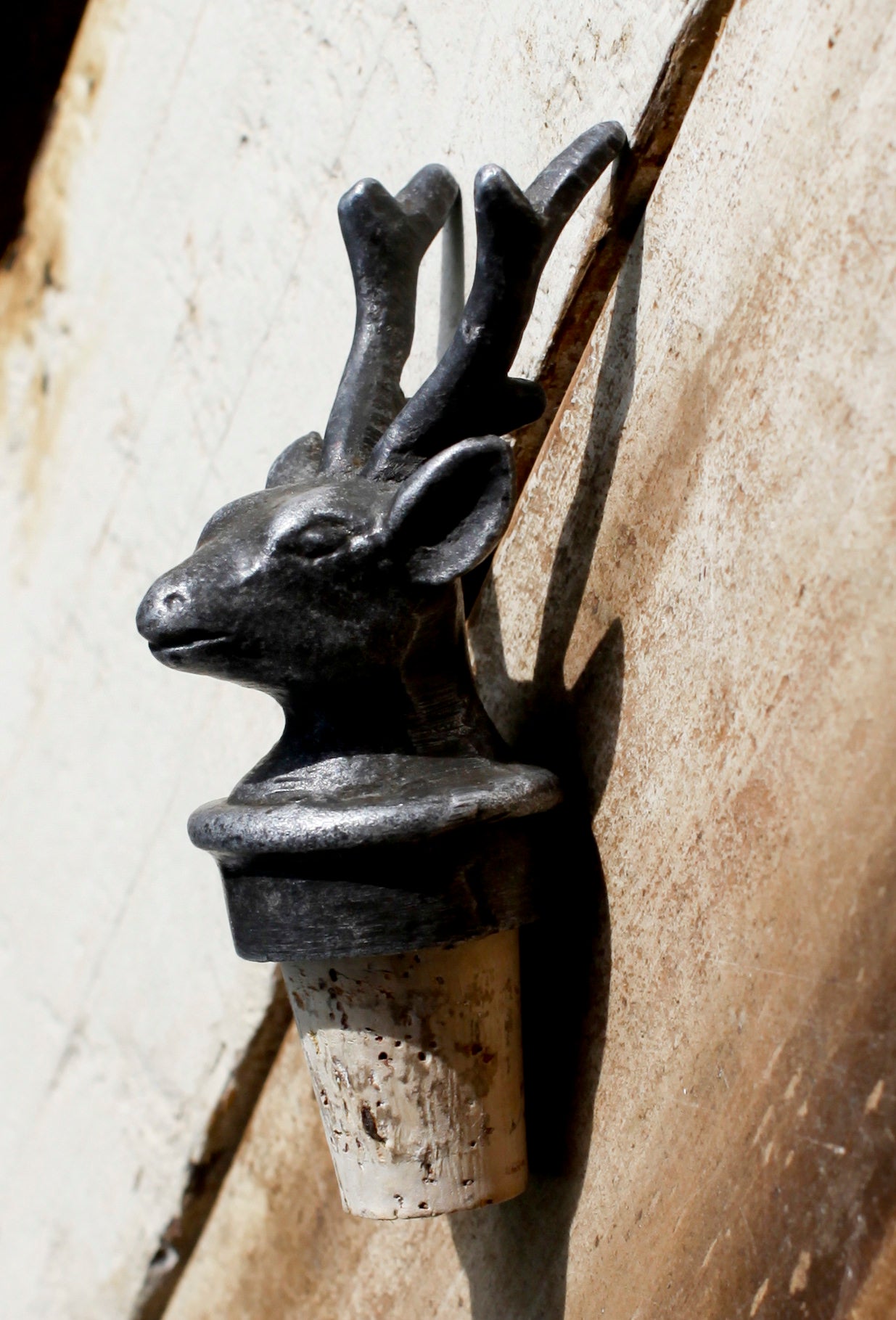Decorative bottle stopper shaped like a deer head on a stone surface