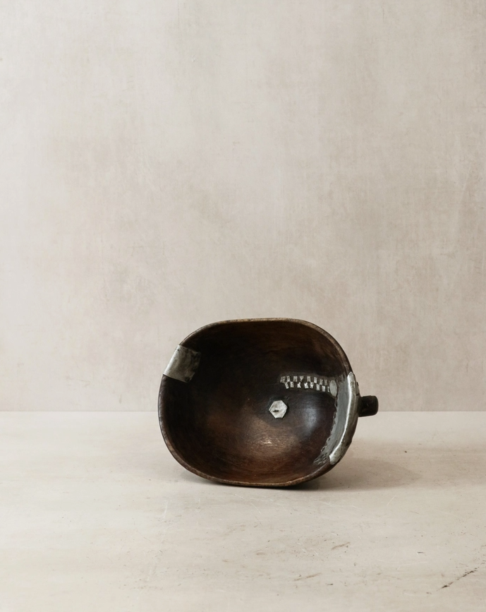 Brown leather bag with metal clasp on a beige background