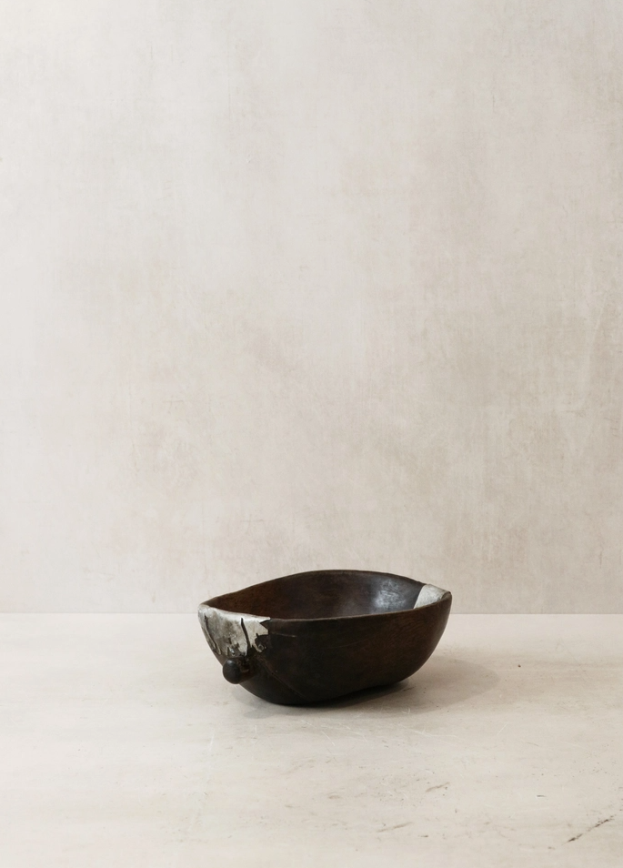Black ceramic bowl on a light wooden surface with a beige wall background