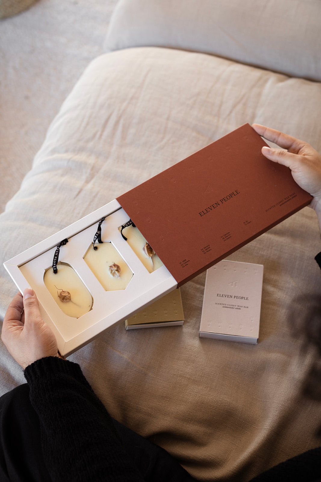 Person holding a branded box with a product inside on a soft surface