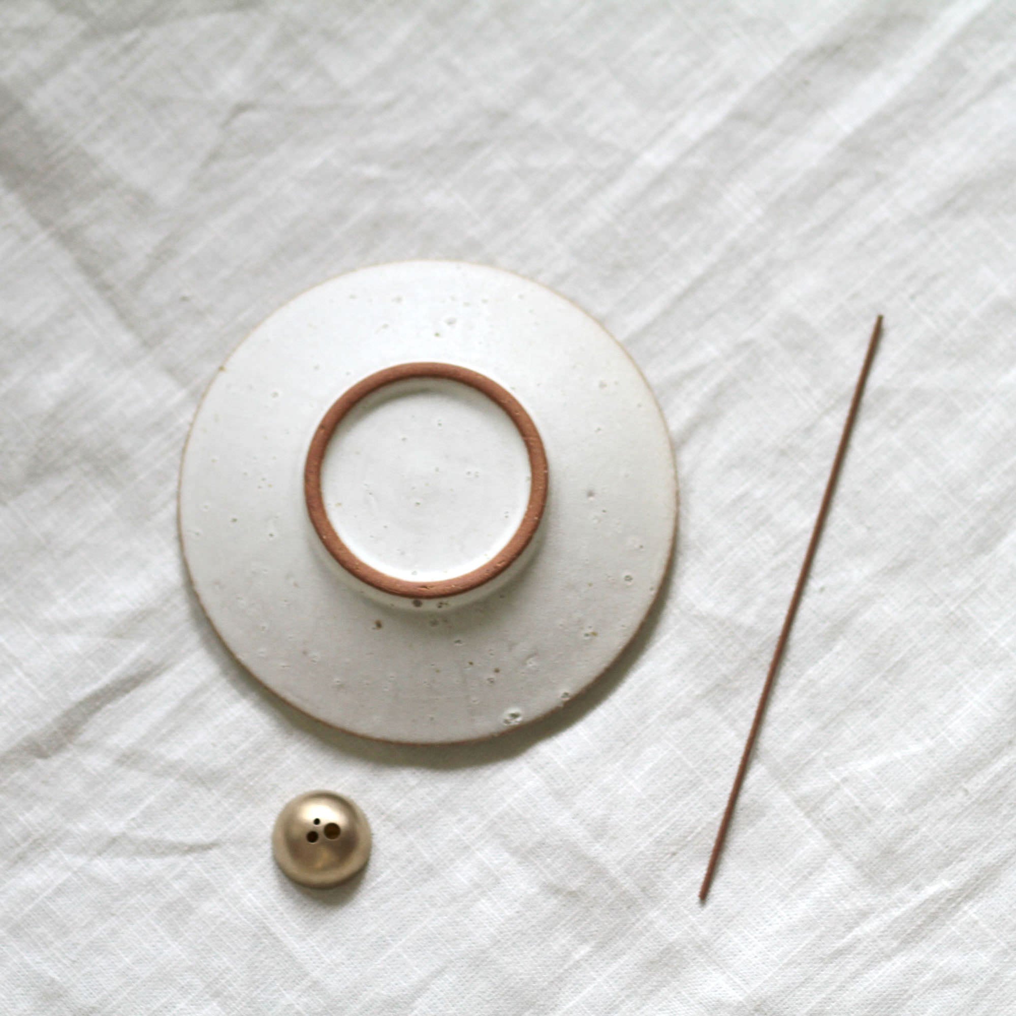 Ceramic dish with a smaller circular object on a textured white surface