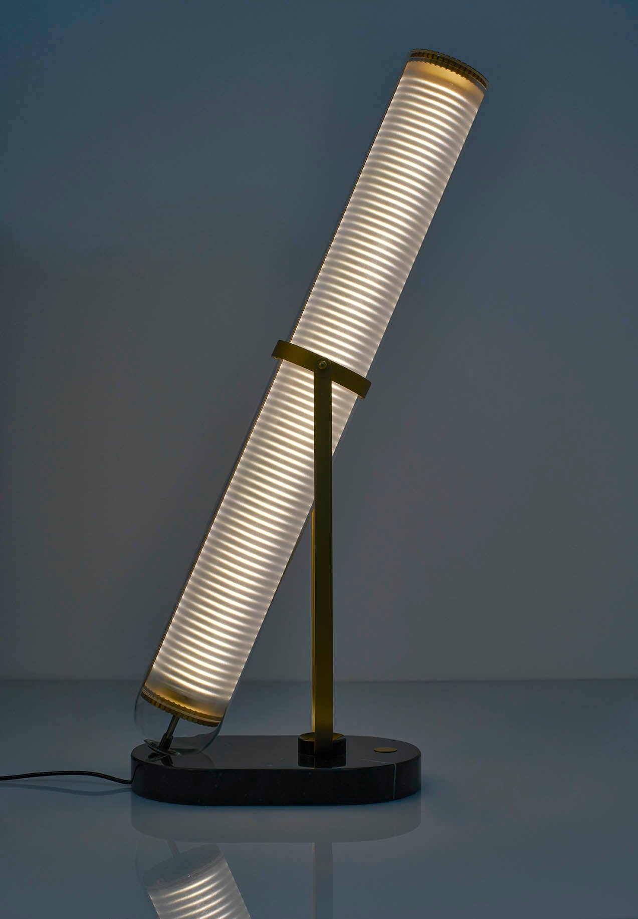 Modern table lamp with cylindrical white shade on a dark background