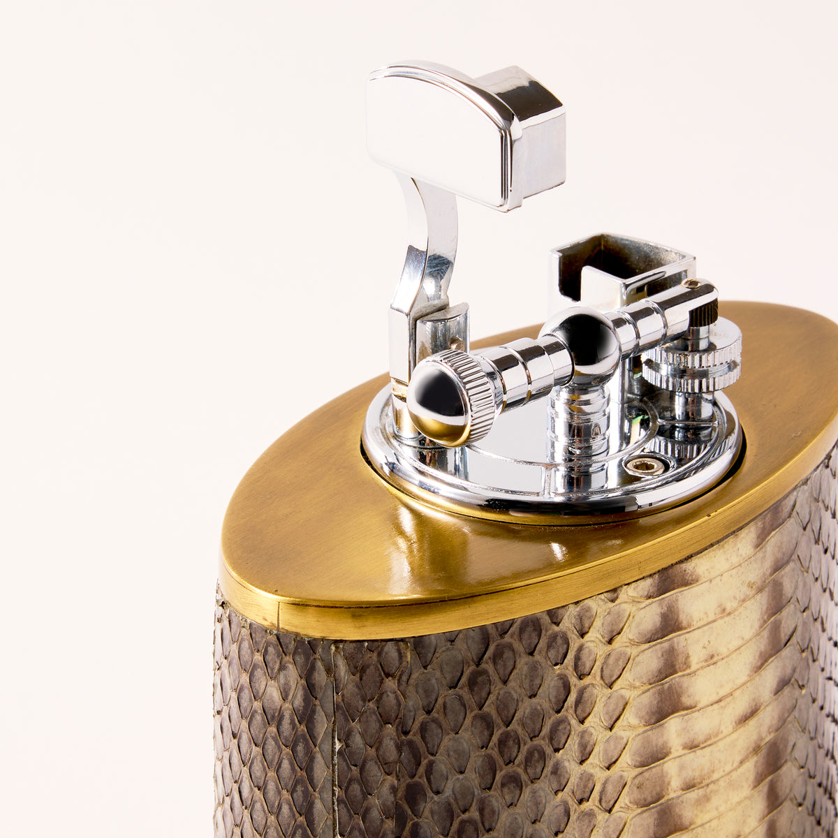 Close-up of a decorative lighter with metallic and textured design on a white background