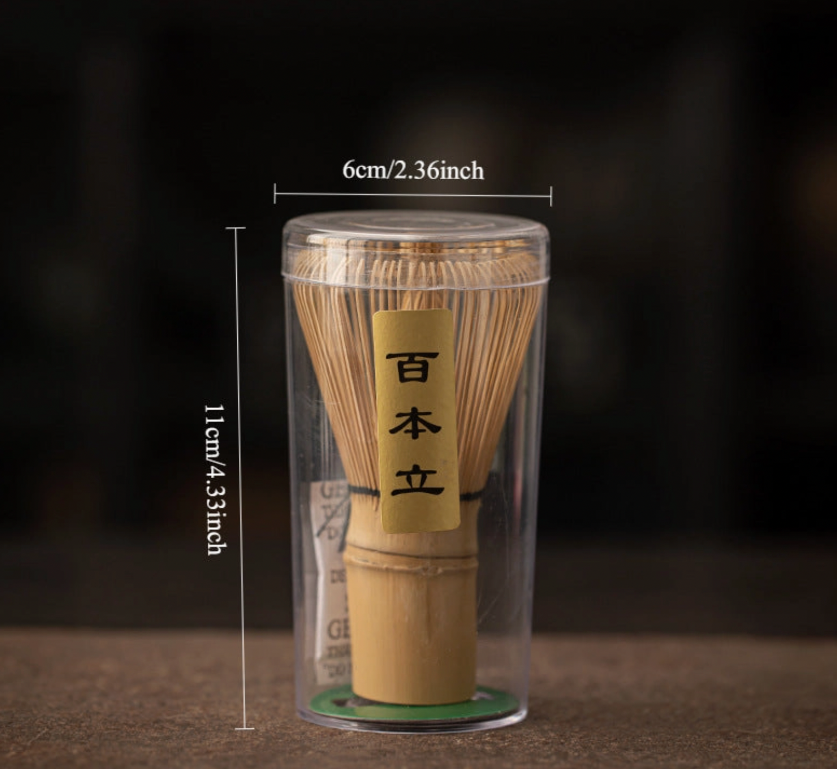 Bamboo whisk in a clear packaging with measurements on a dark background