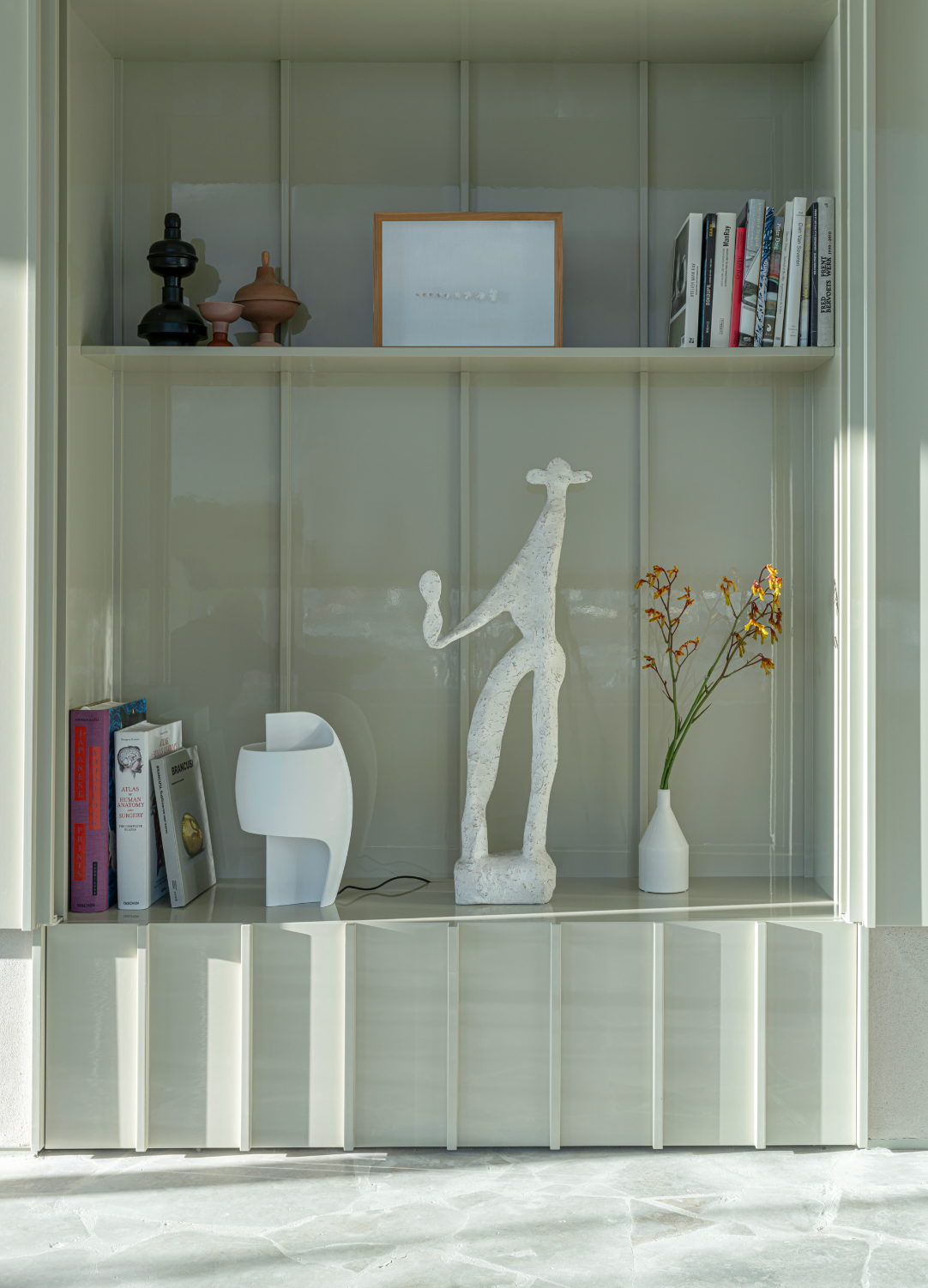Shelving unit with decorative items including a sculpture, books, and a vase.
