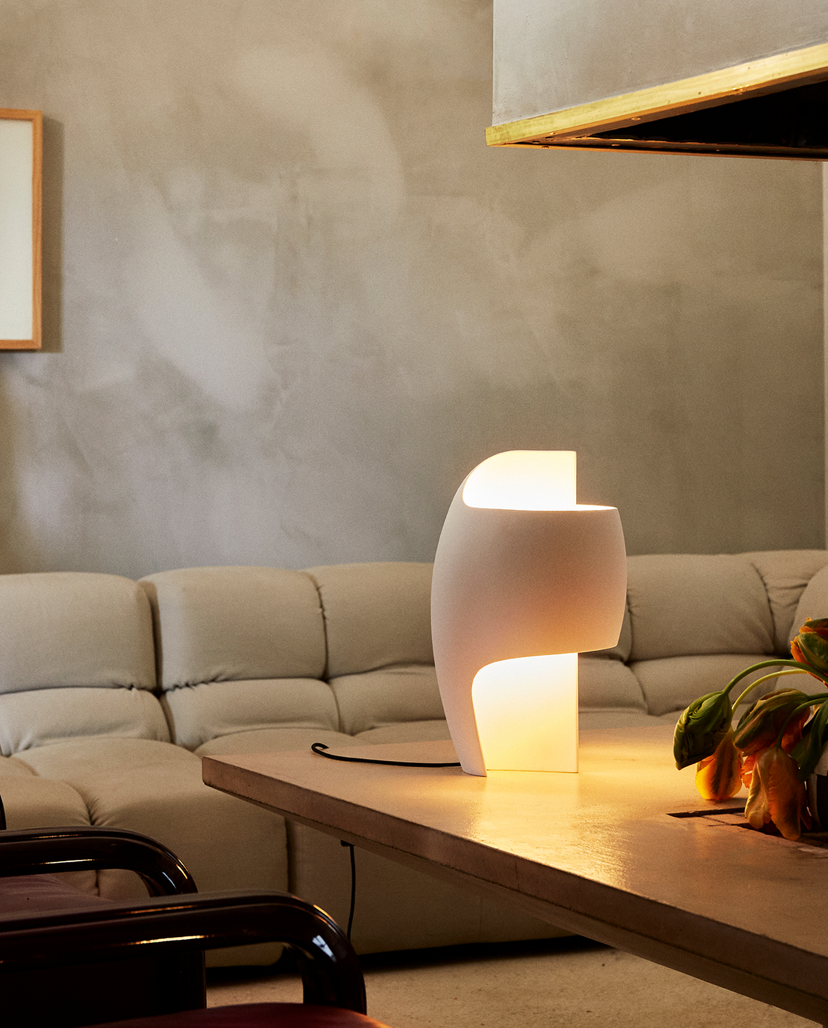 Modern living room with a beige sectional sofa, wooden coffee table, and a stylish lamp.