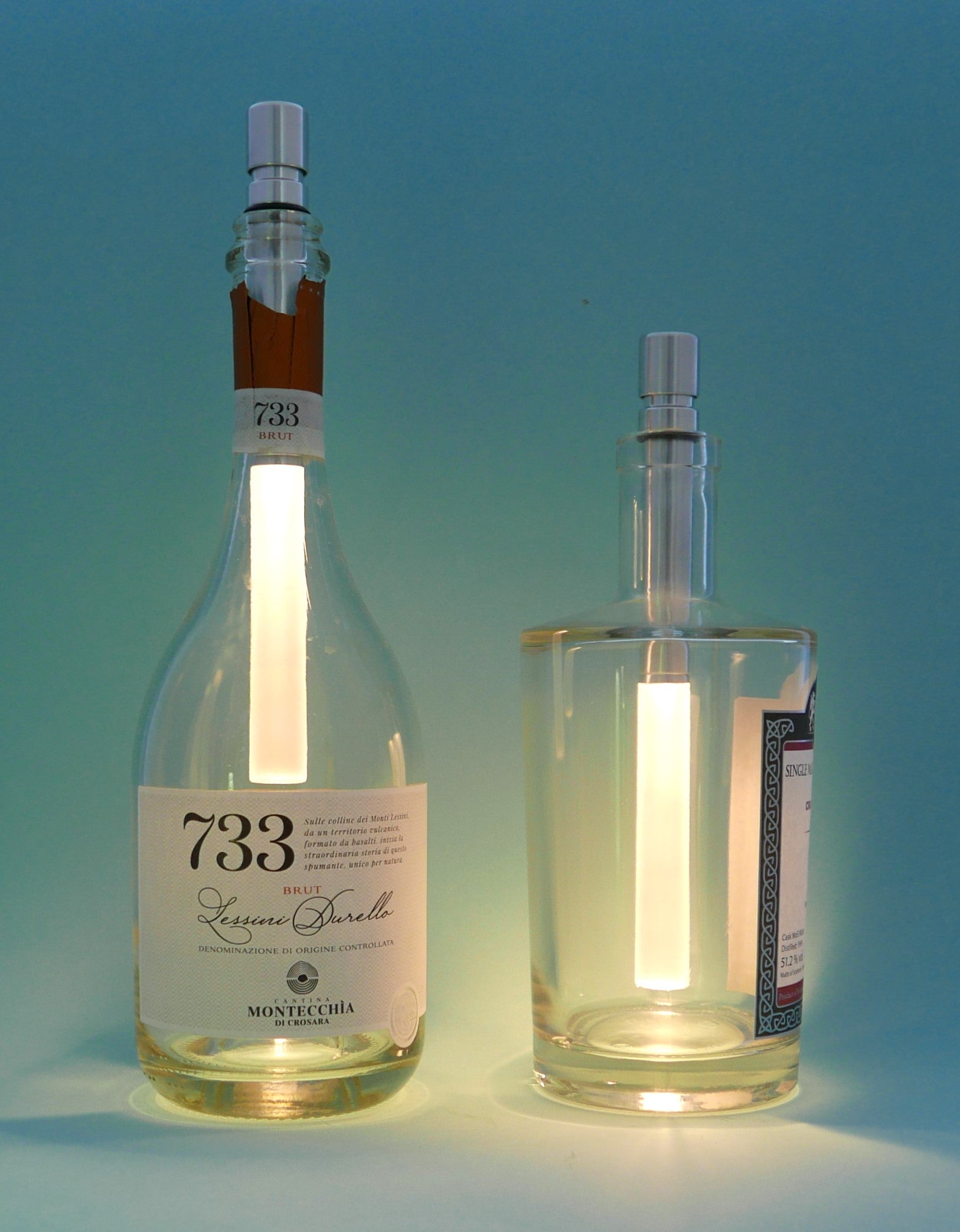 Two glass bottles repurposed as lamps with visible labels on a gradient blue background