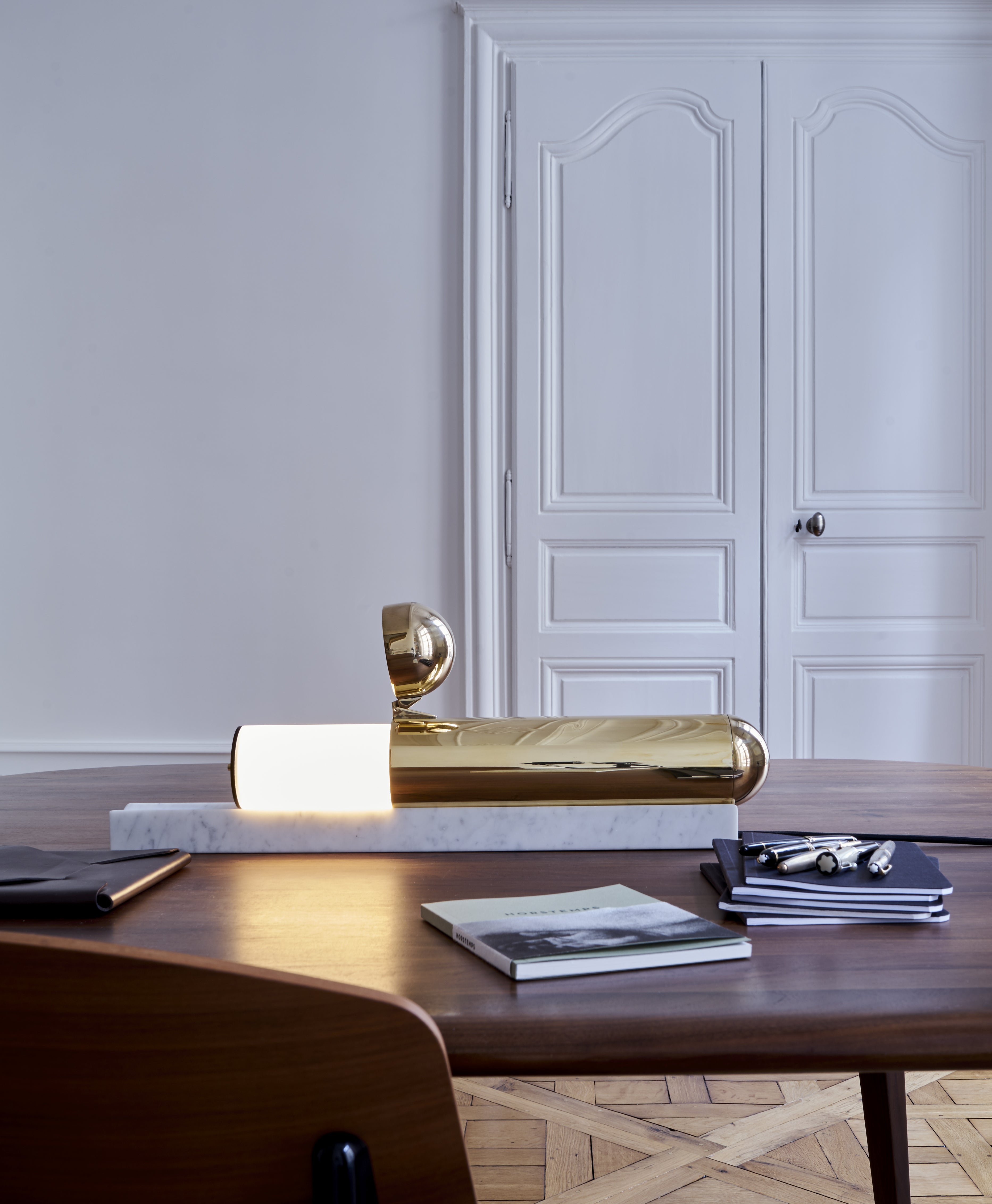 Gold decorative object on a wooden table with a white wall and door in the background