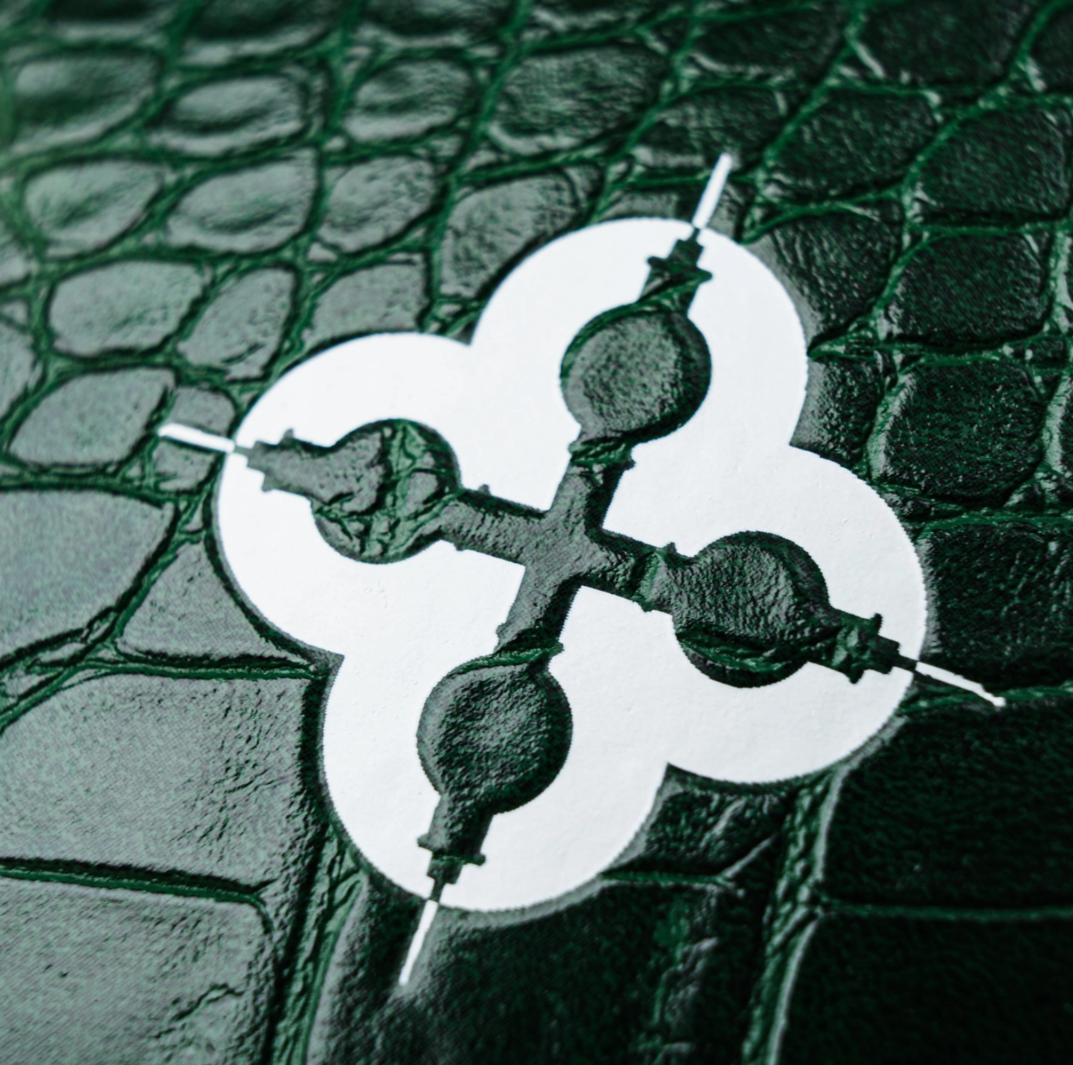 Decorative metal object with a circular design on a textured green background