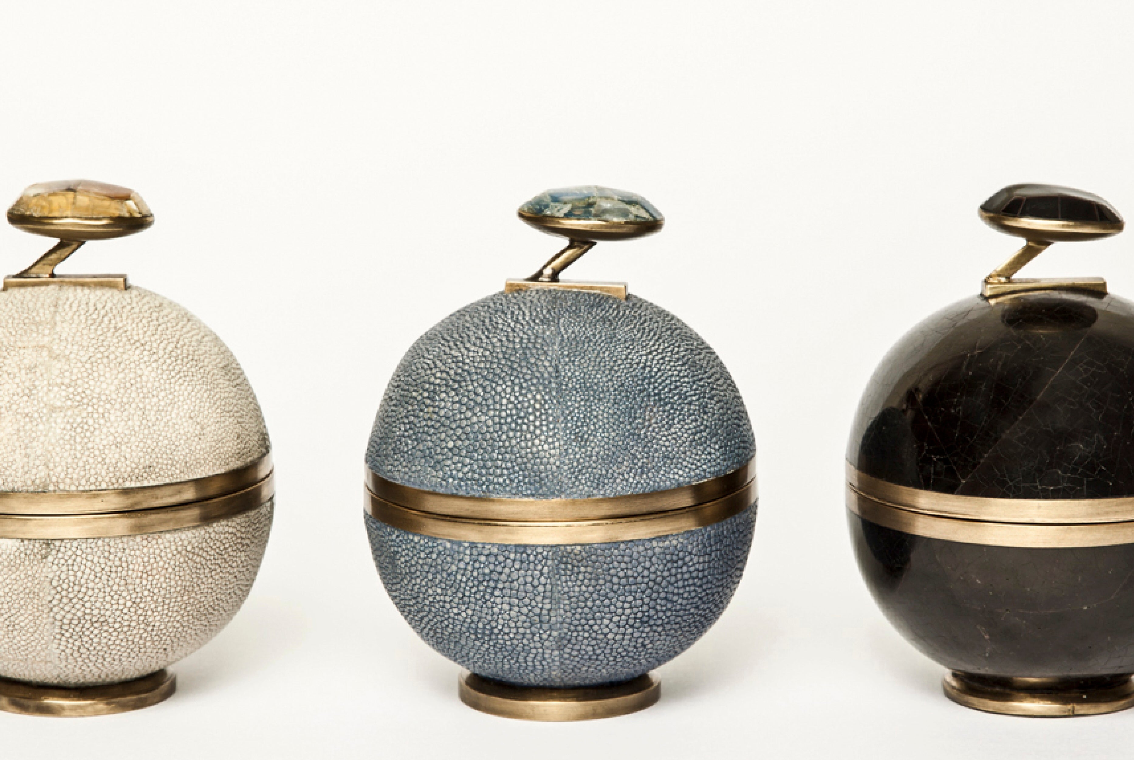 Three decorative urns with textured surfaces and gold accents on a white background