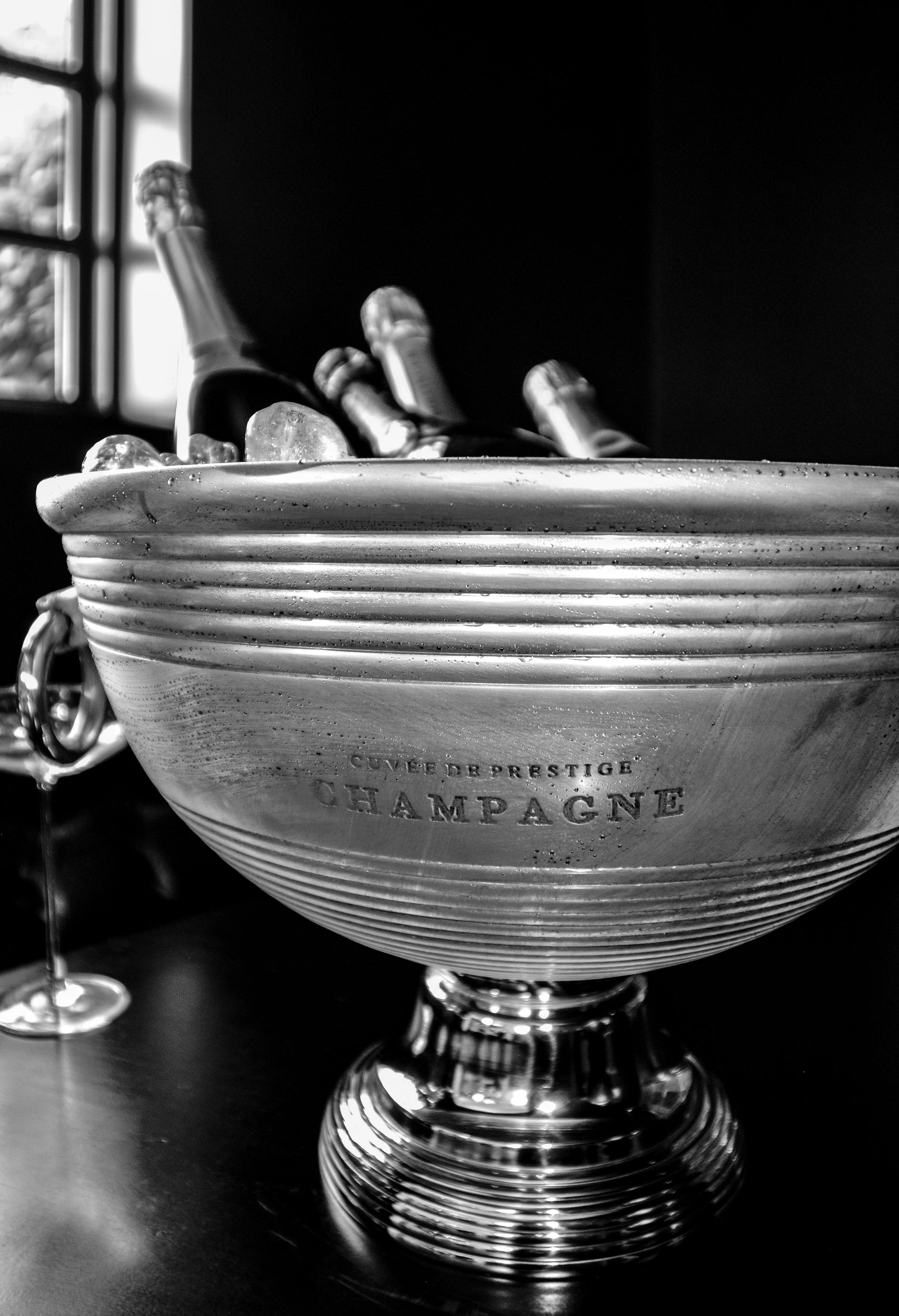 Silver champagne bowl with bottles inside on a dark surface