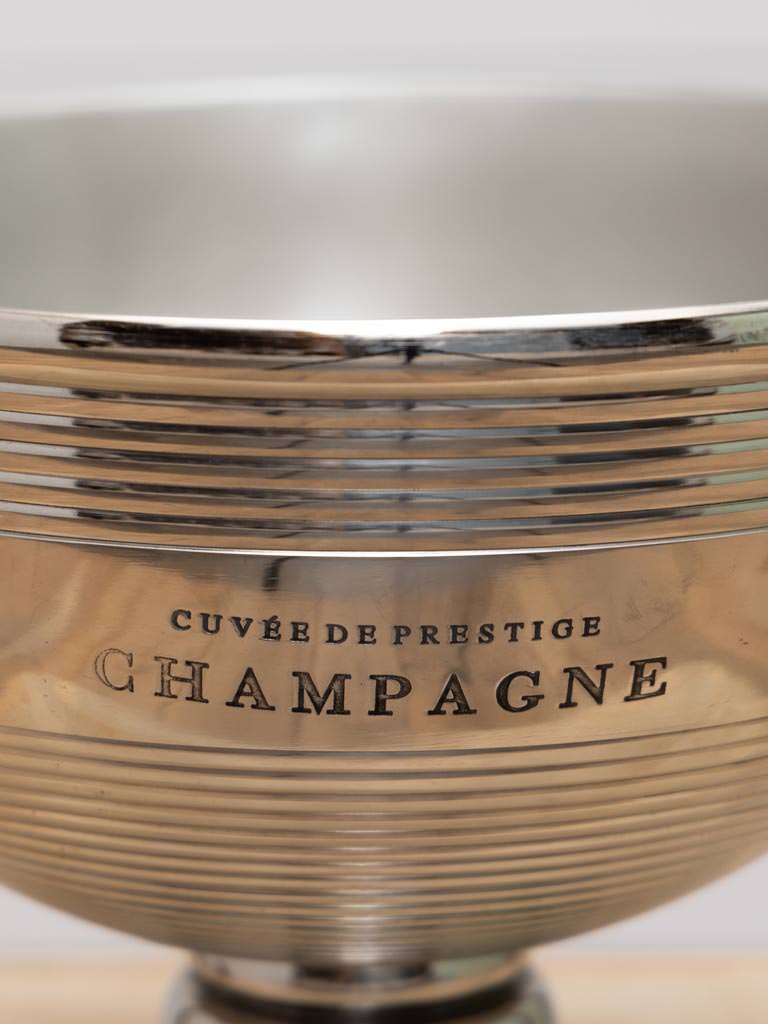 Silver champagne container with 'Cçuvée de Prestige Champagne' engraving on a white background