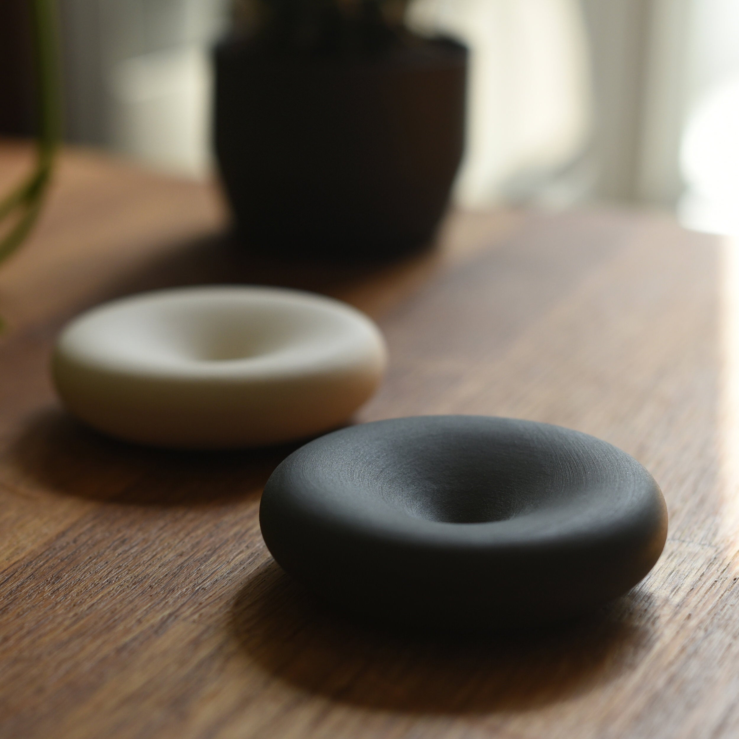 Two ceramic donut-shaped objects on a wooden surface with a blurred background