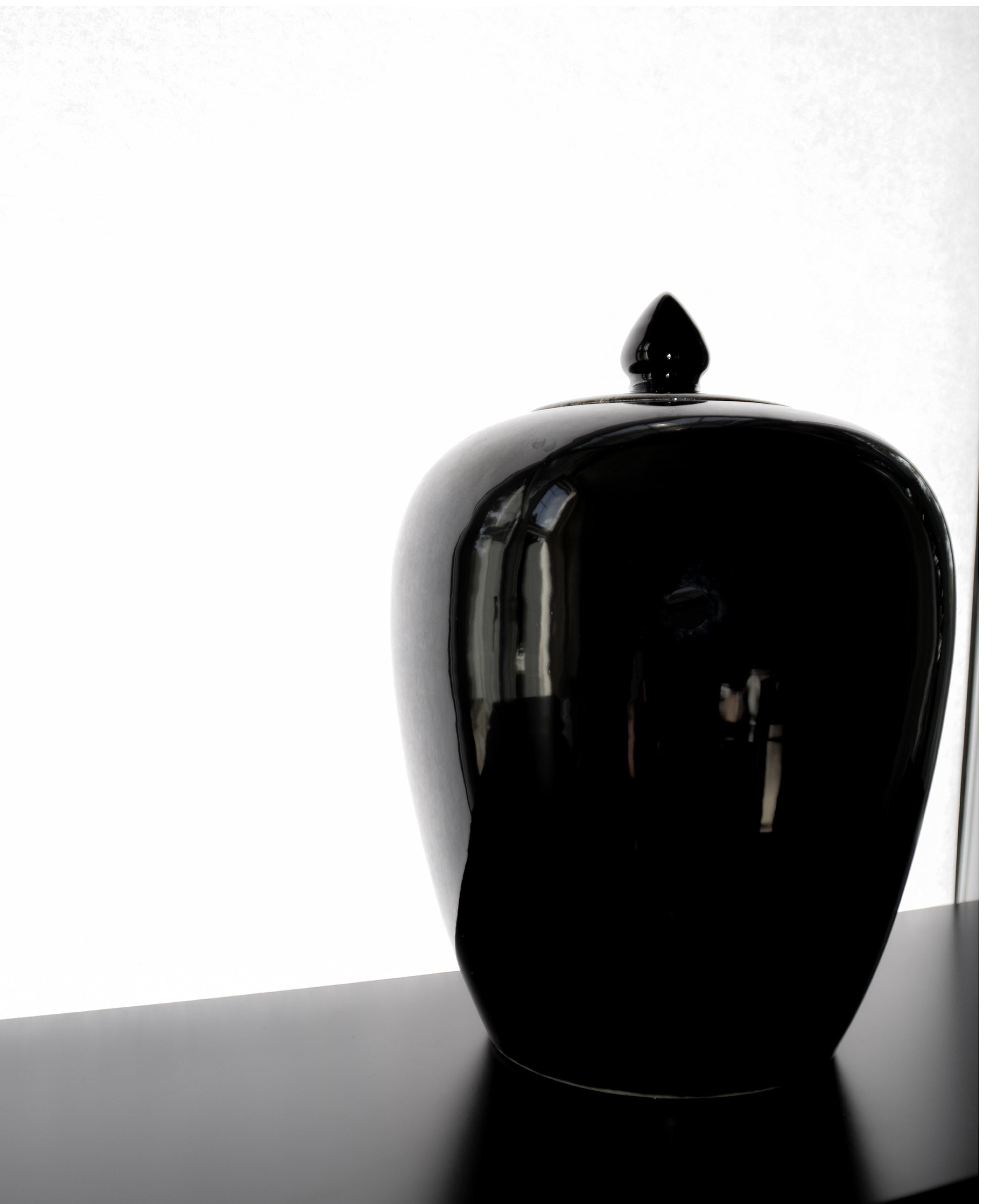 Black ceramic jar with a lid on a white background