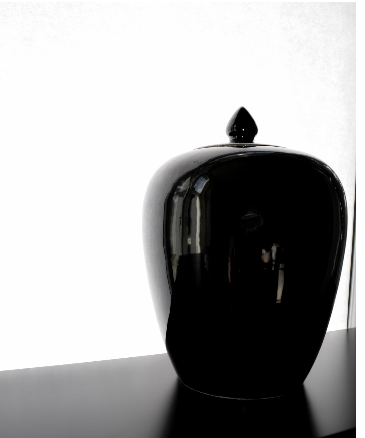 Black ceramic jar with a lid on a white background