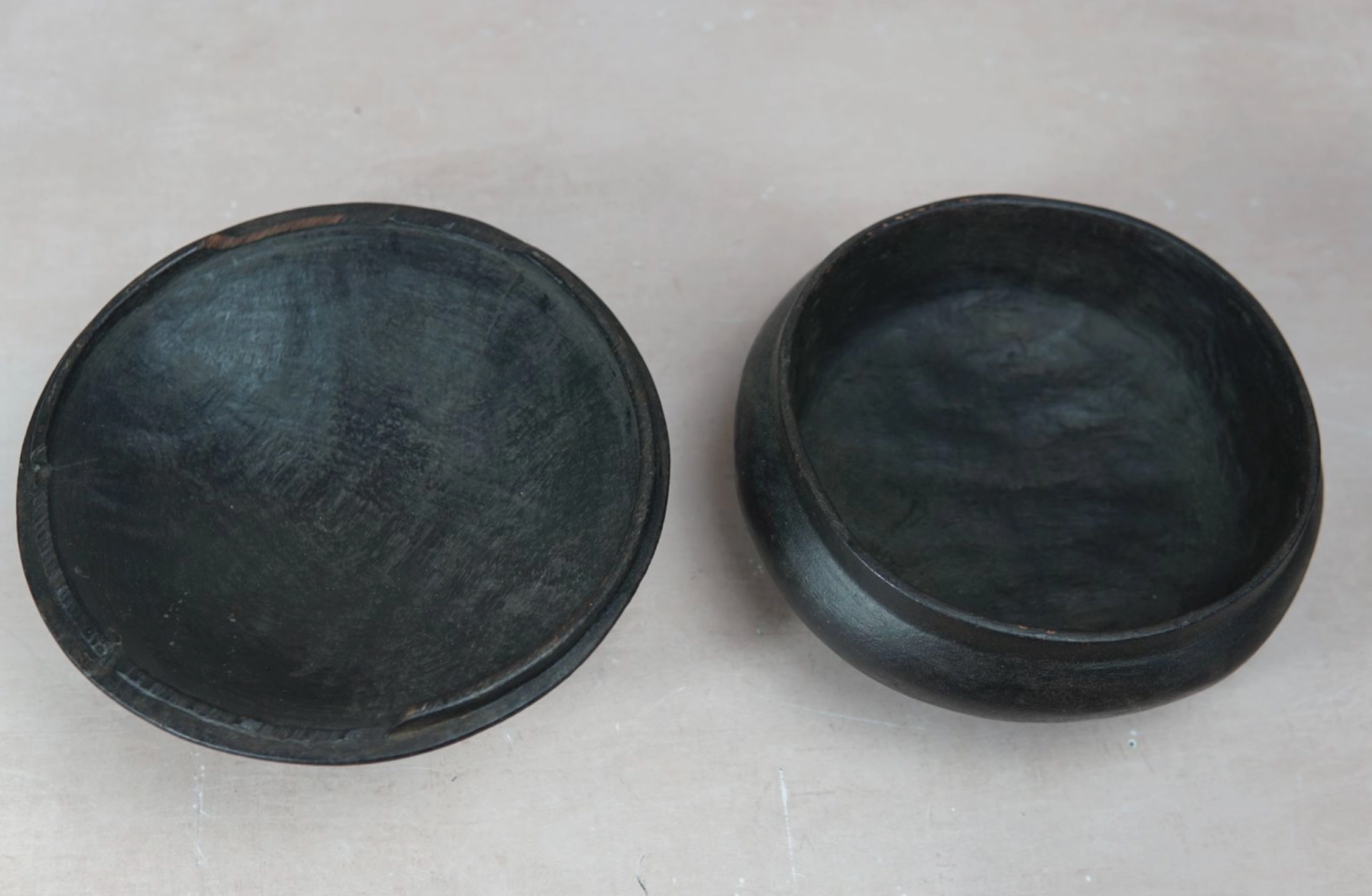 Two black ceramic bowls on a gray surface
