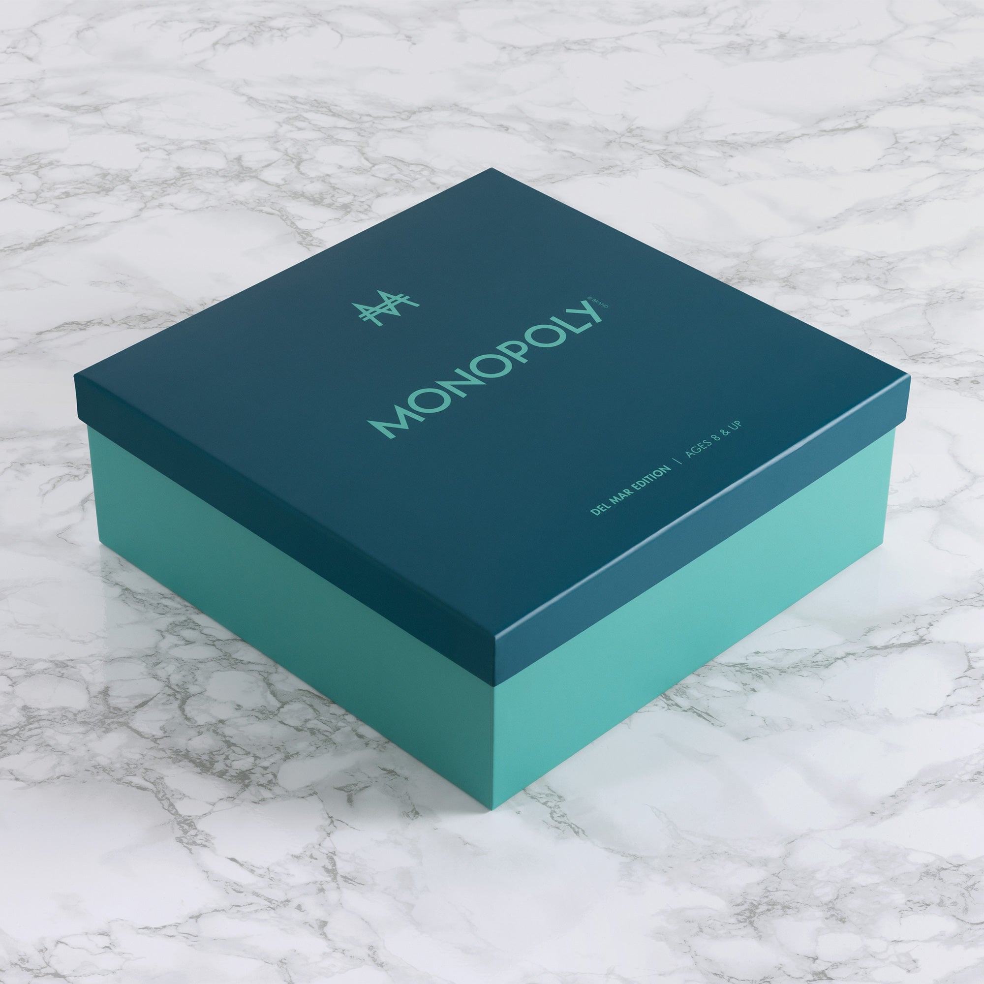 Teal Monopoly game box on a marble surface