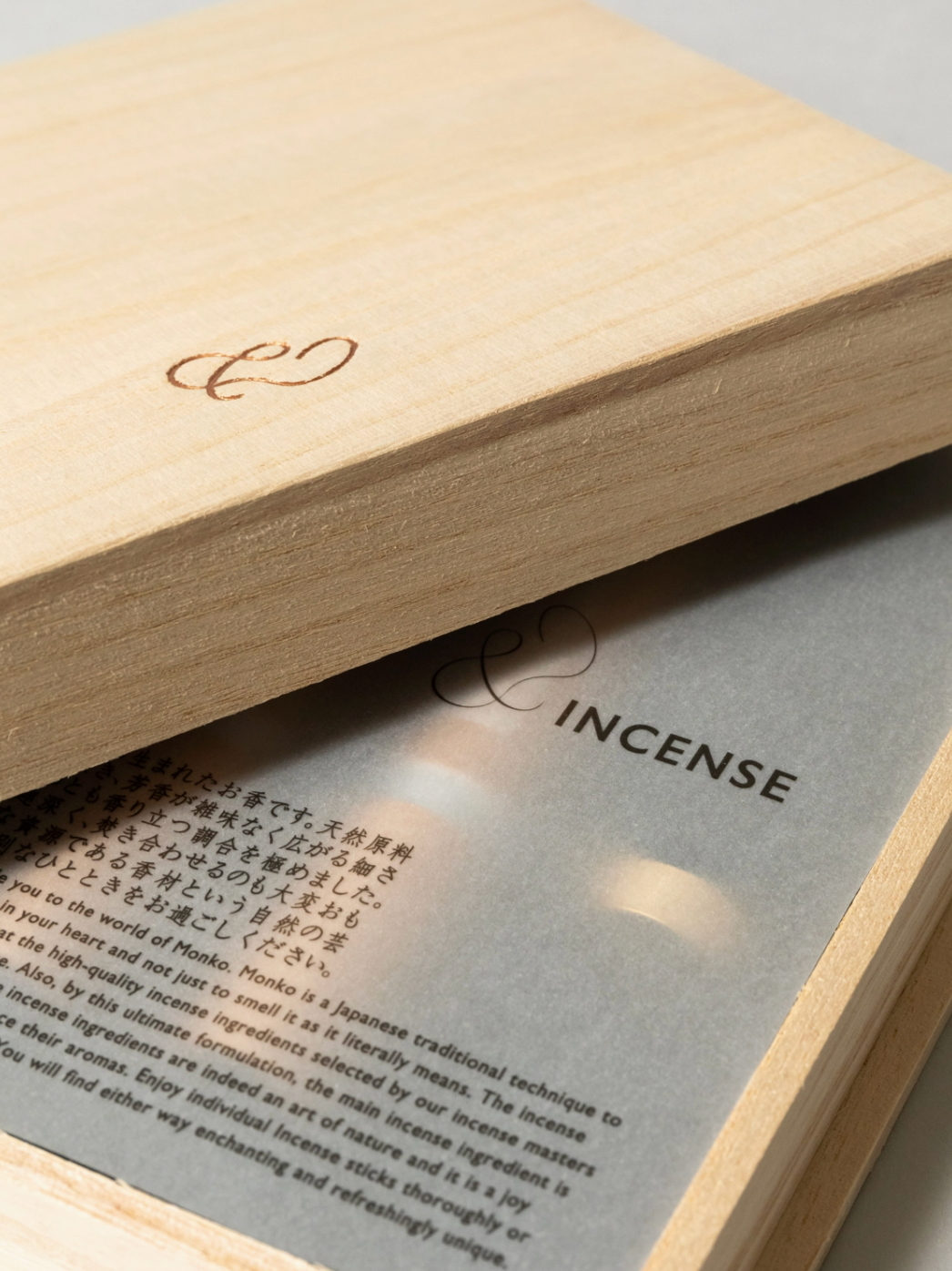 Incense packaging with wooden lid and gray interior displaying text.
