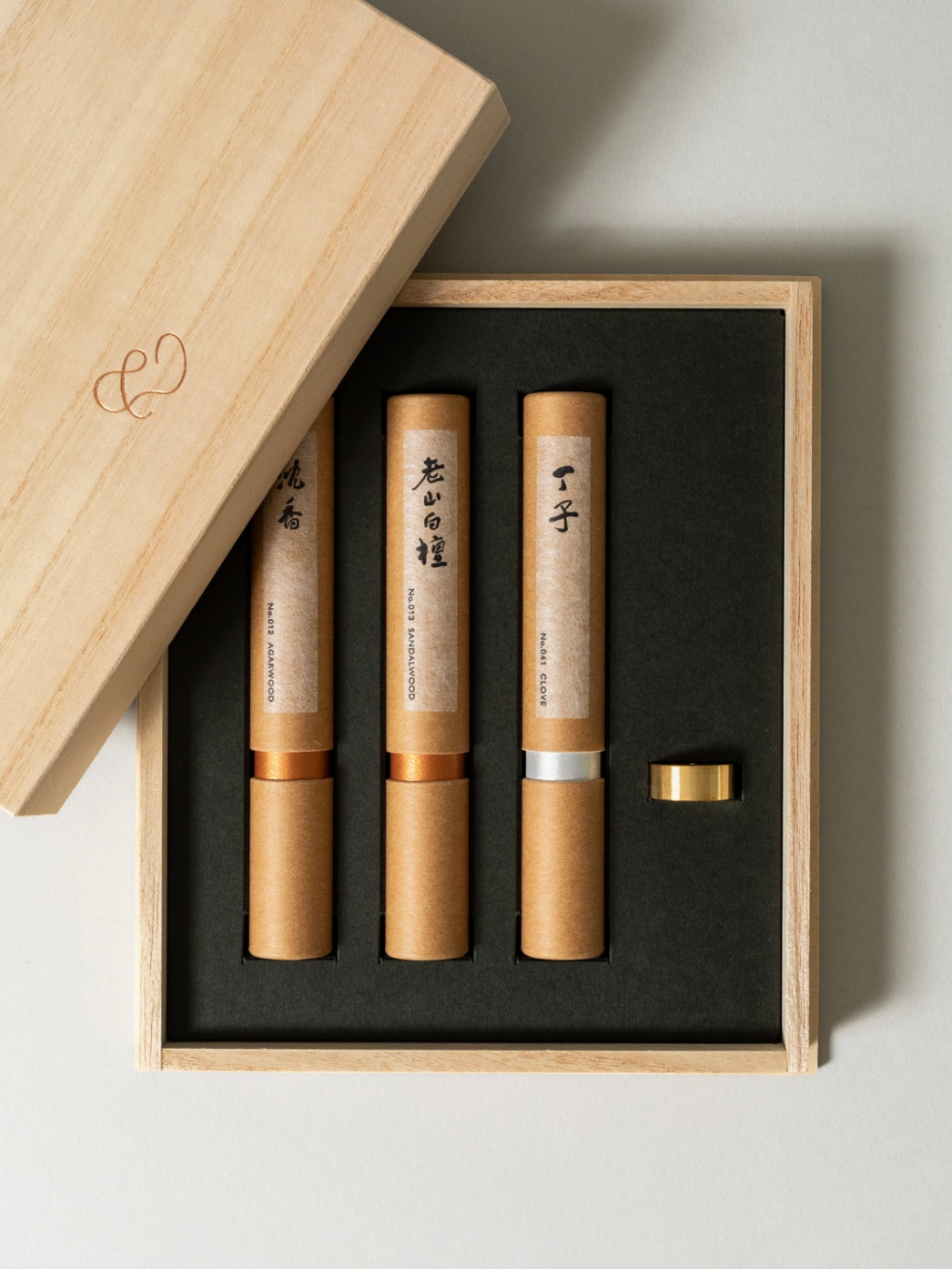 Three cylindrical products in a wooden box with a black interior