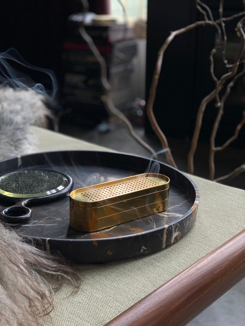 Brass Incense Burner on a dark tray with a blurred background