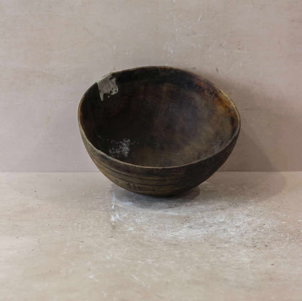 Dark brown ceramic bowl on a light beige surface with a neutral background