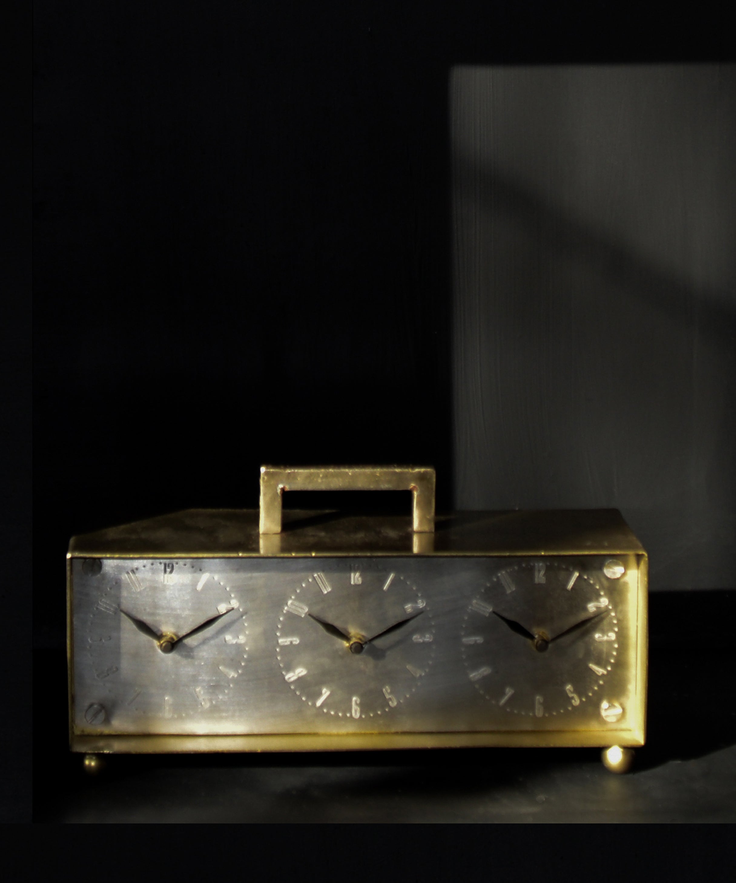 Vintage-style brass clock with dual faces on a dark background