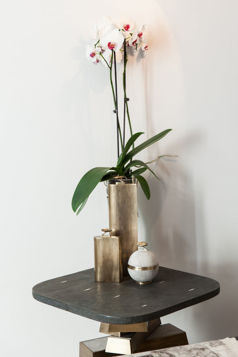 Decorative table with a vase of flowers and a lamp against a white wall