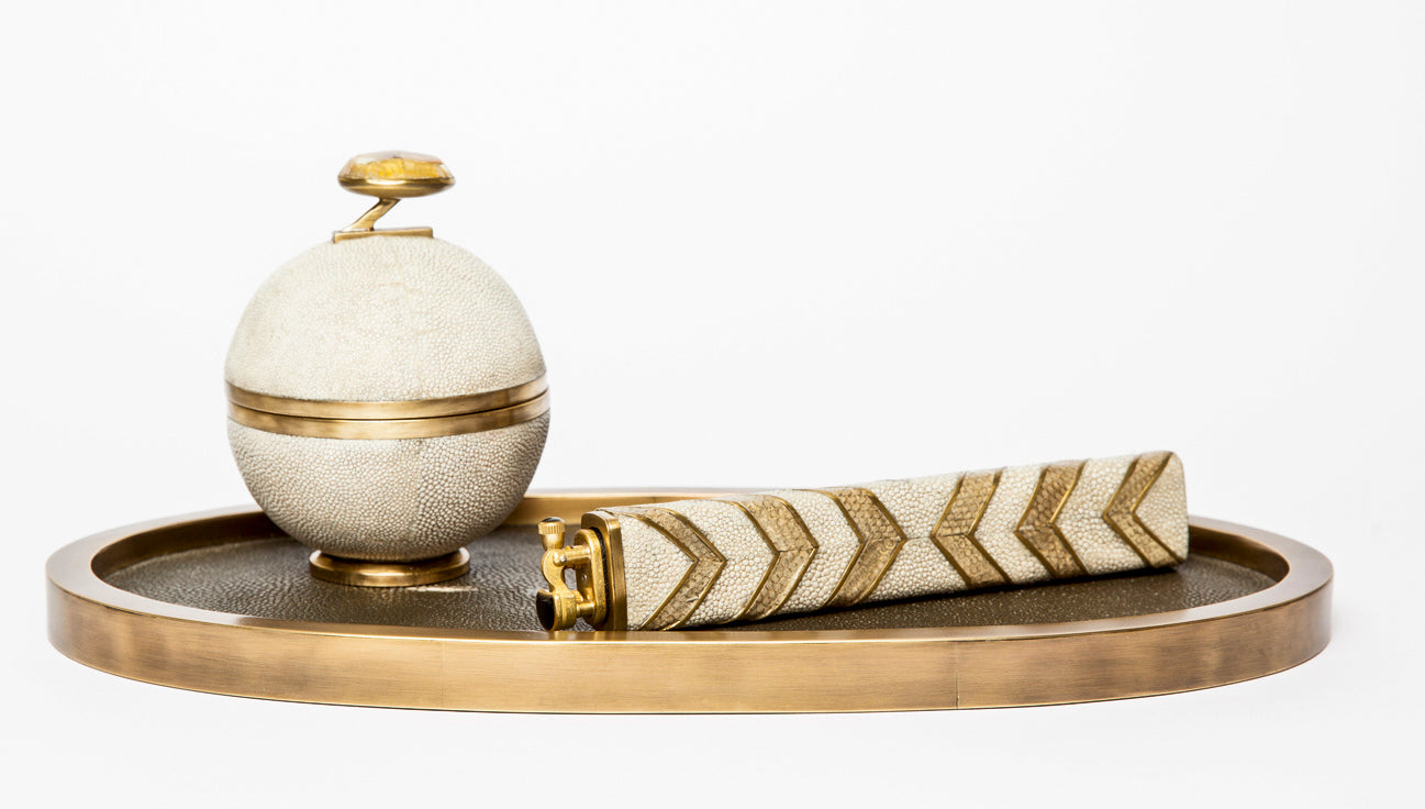 Decorative items including a spherical container and a cylindrical object on a tray with a white background