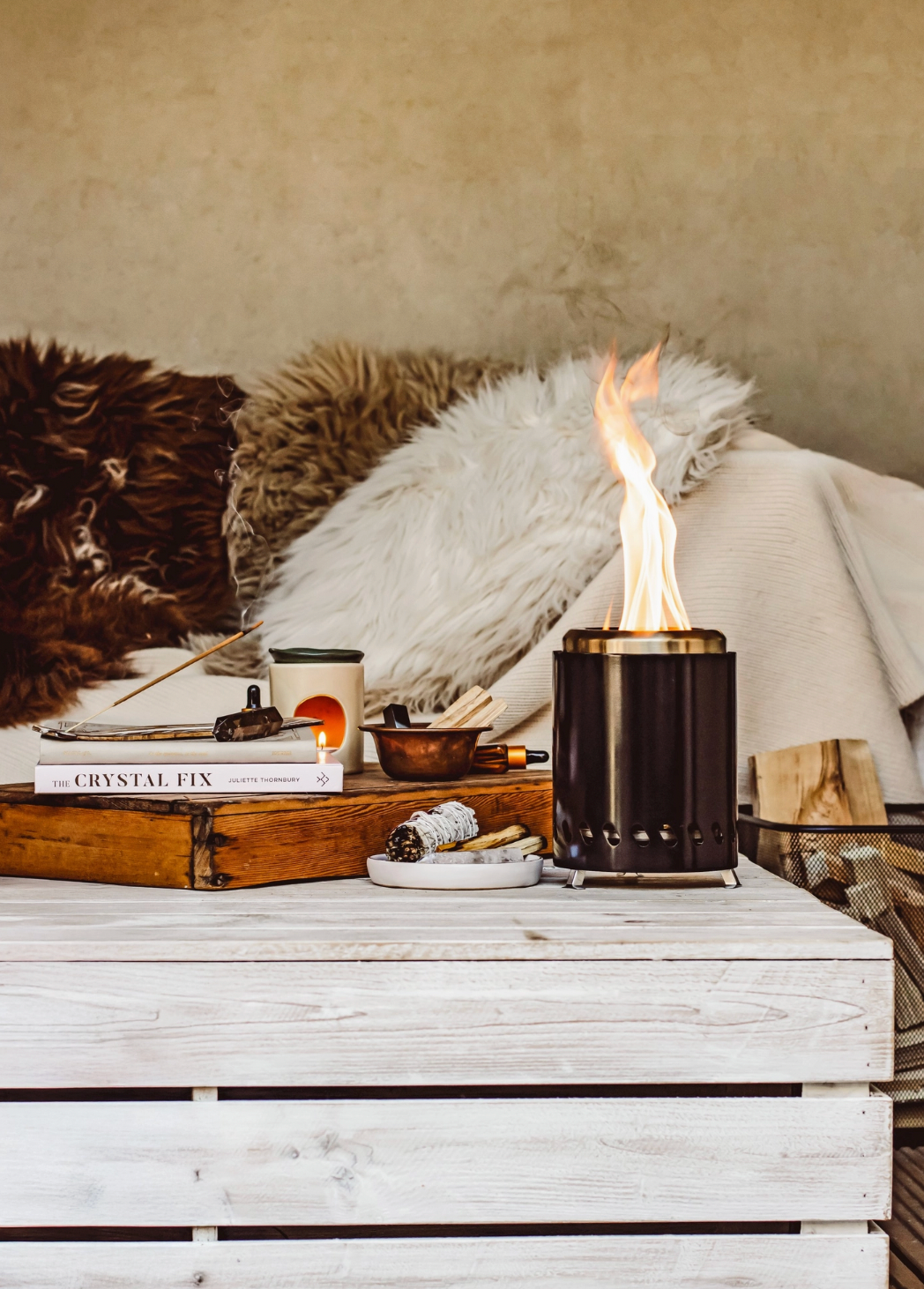 Small black lantern with flame on a wooden surface with books and decorative items.