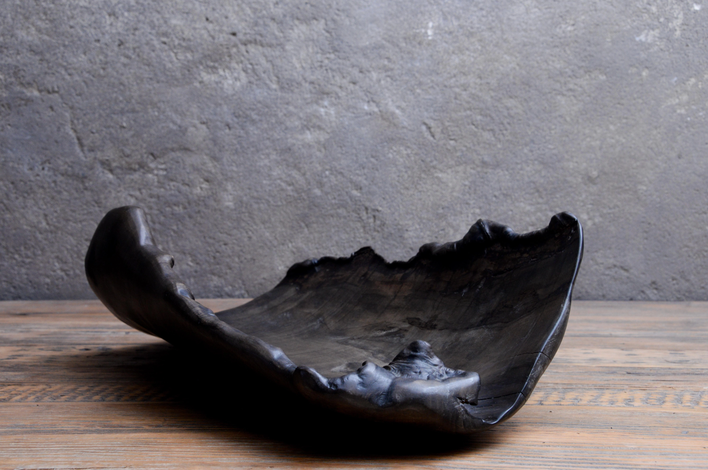 Black ceramic bowl on a wooden surface with a gray stone wall background