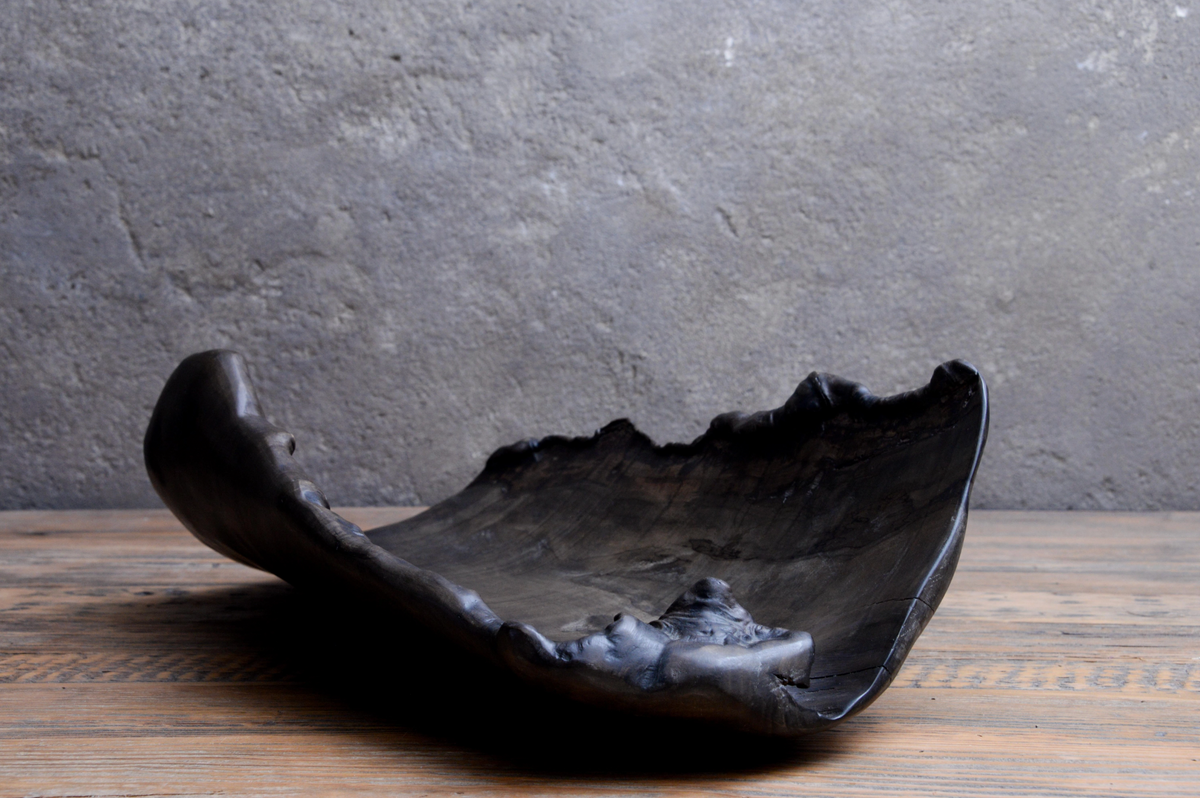 Black ceramic bowl on a wooden surface with a gray stone wall background