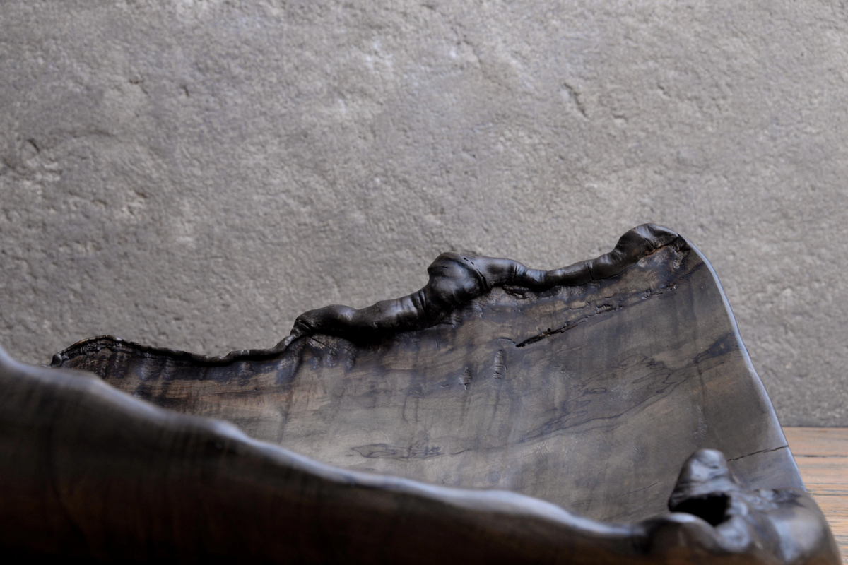Bronze sculpture of a reclining figure against a gray wall