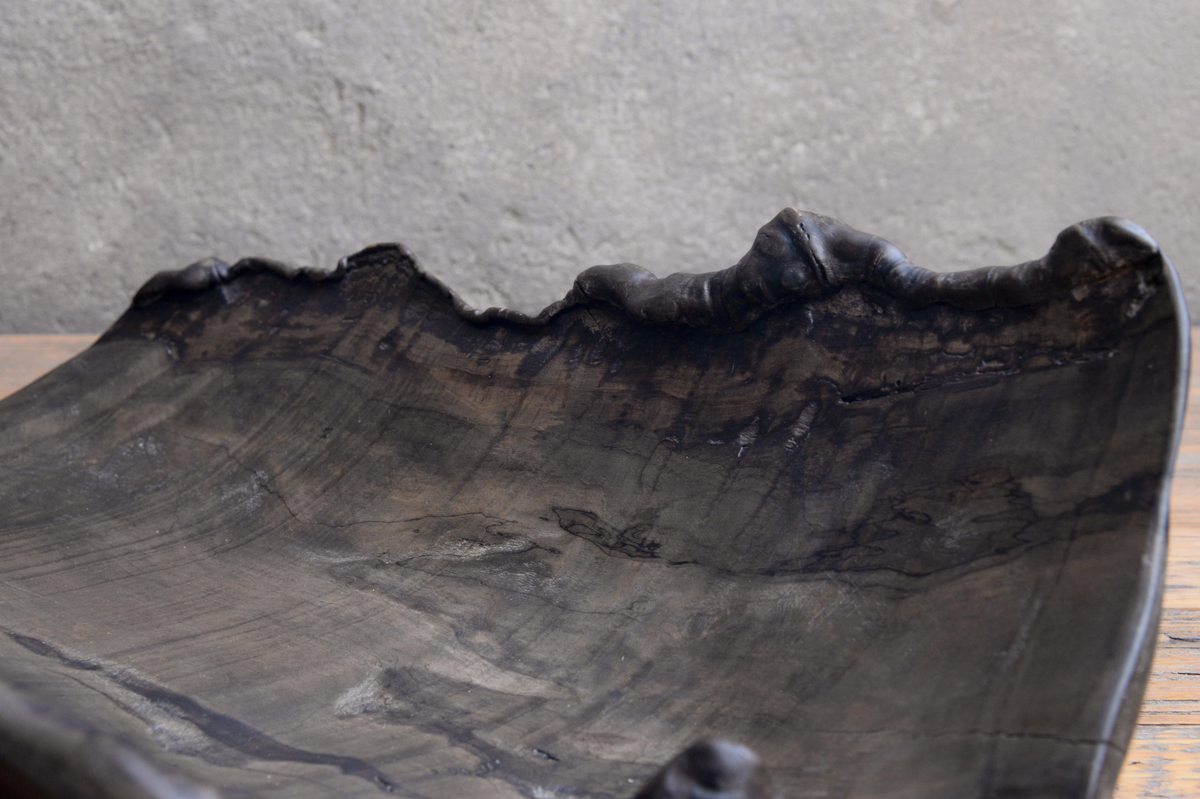 Black stone-like surface with natural texture on a gray background