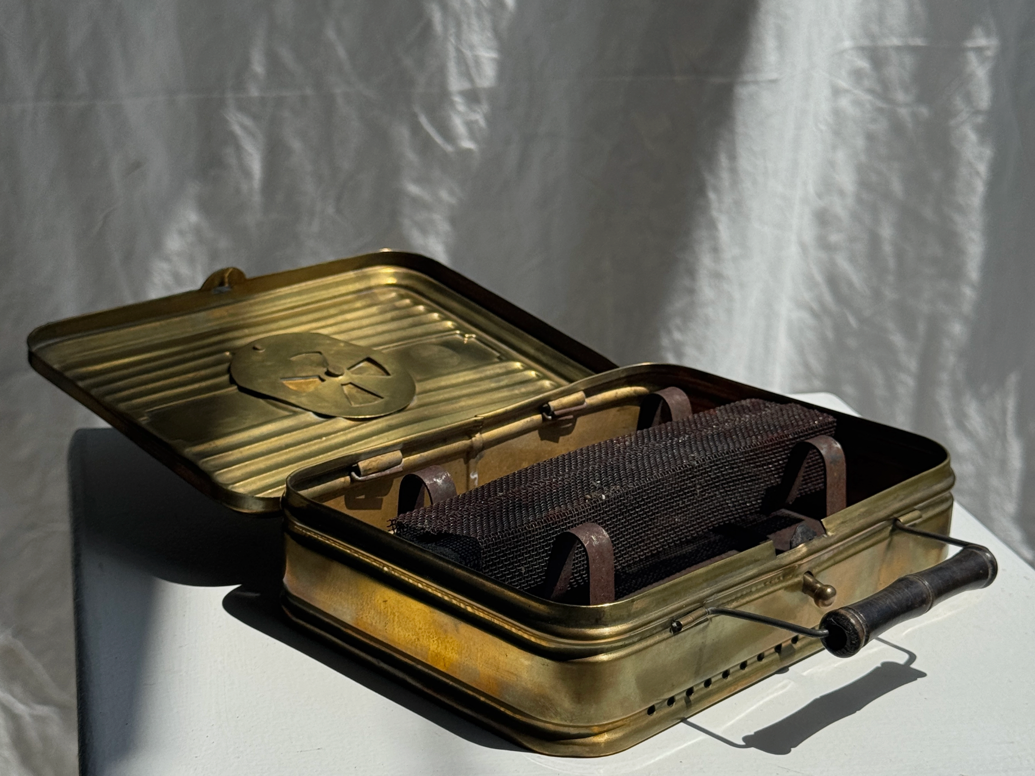 Vintage-style suitcase with a metallic finish and a prominent emblem on a white background