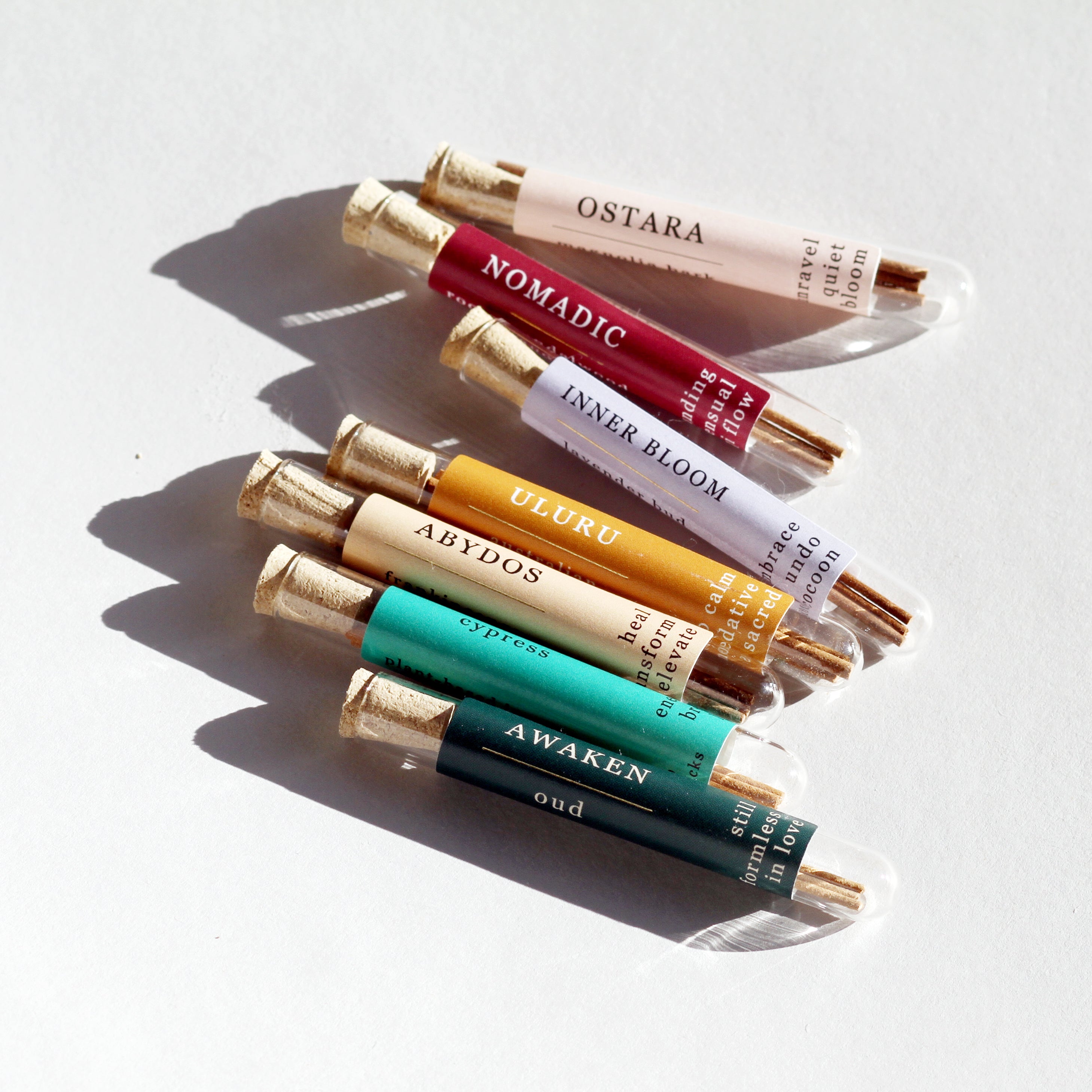 Set of small bottles with gold caps on a light background. Incense sample pack