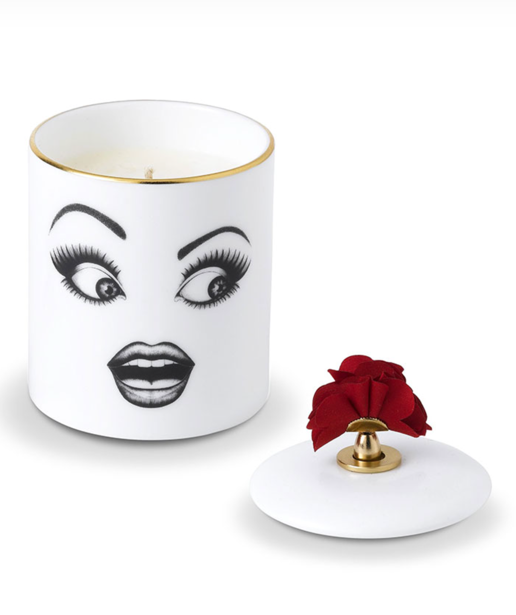 Candle with face design and red rose on lid against a white background