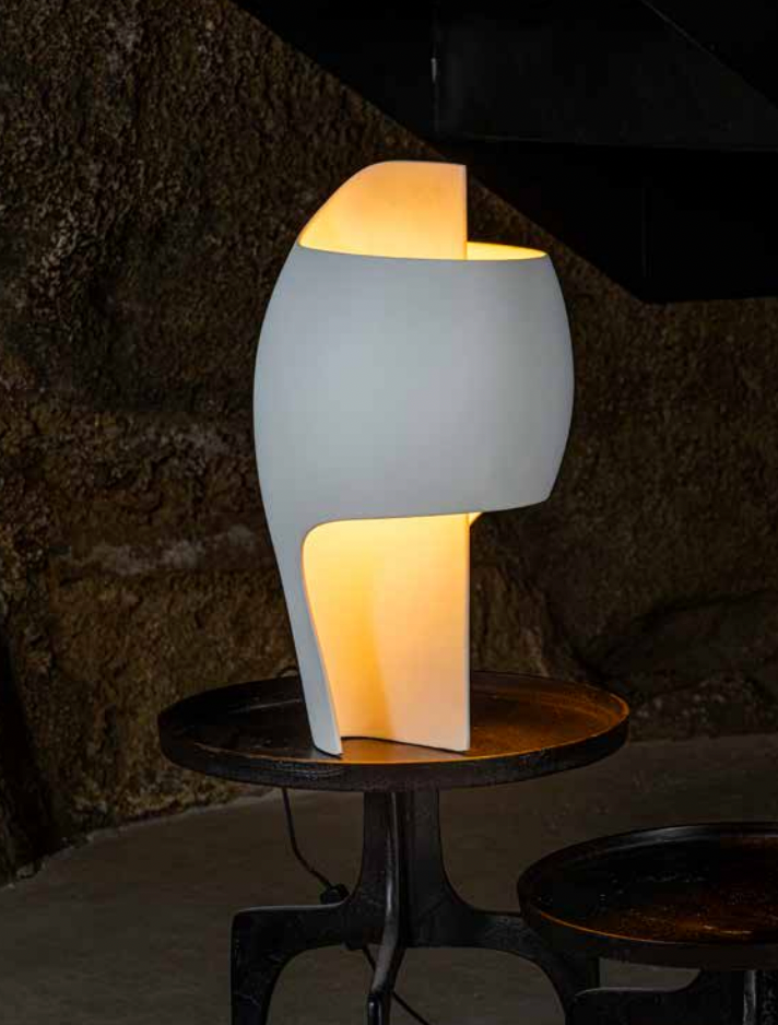 Modern table lamp with a gray base and yellowish light on a dark background