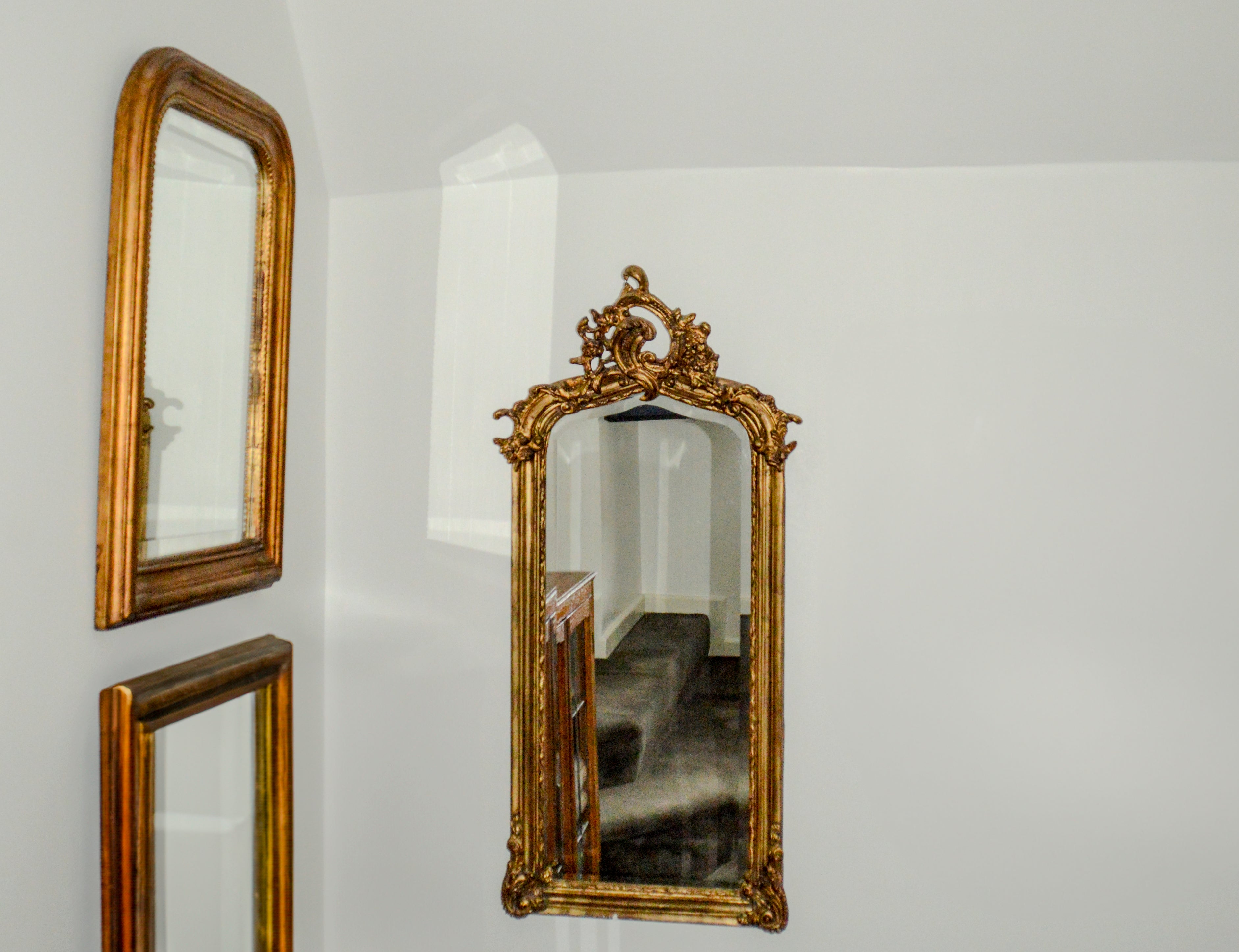 Three ornate gold mirrors on a white wall