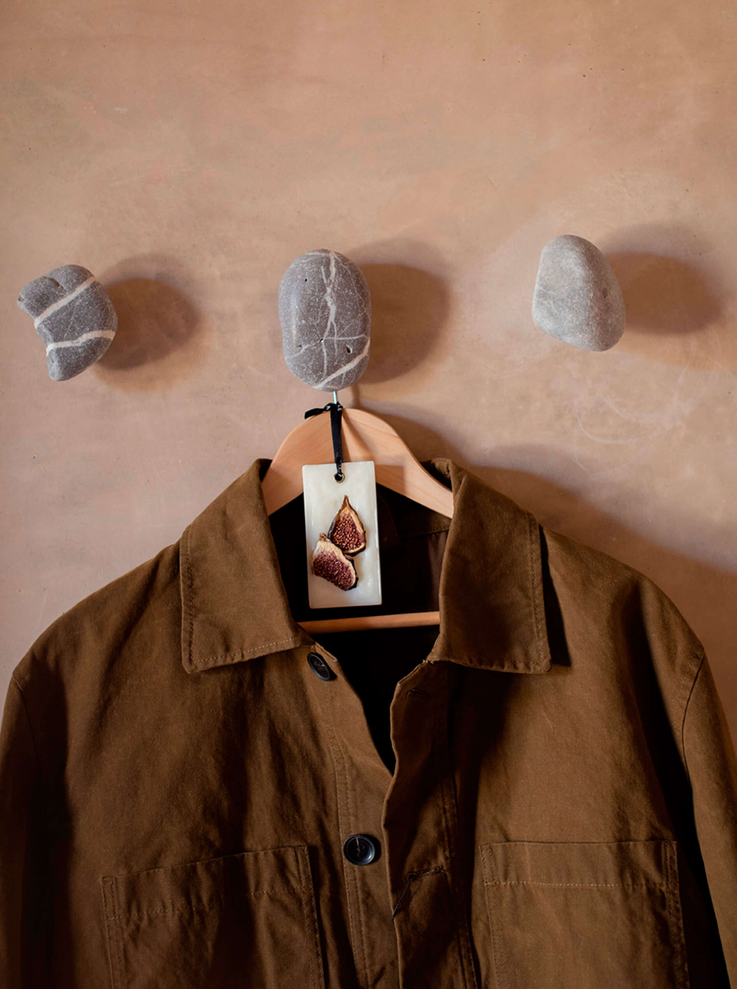 Brown jacket hanging on a wall with pebbles