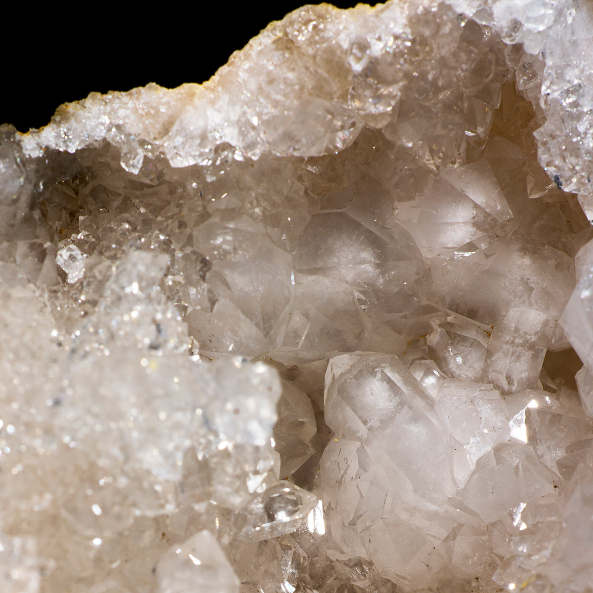 Close-up of a crystal formation with clear and beige crystals on a black background