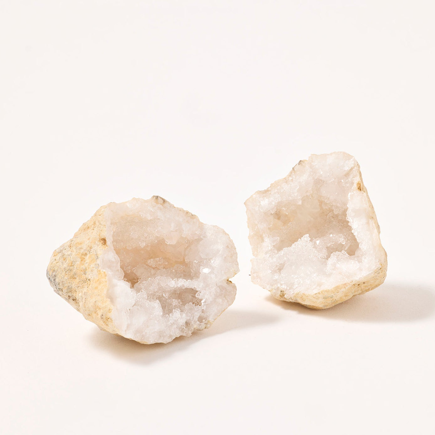 Two white crystal geodes on a light beige background