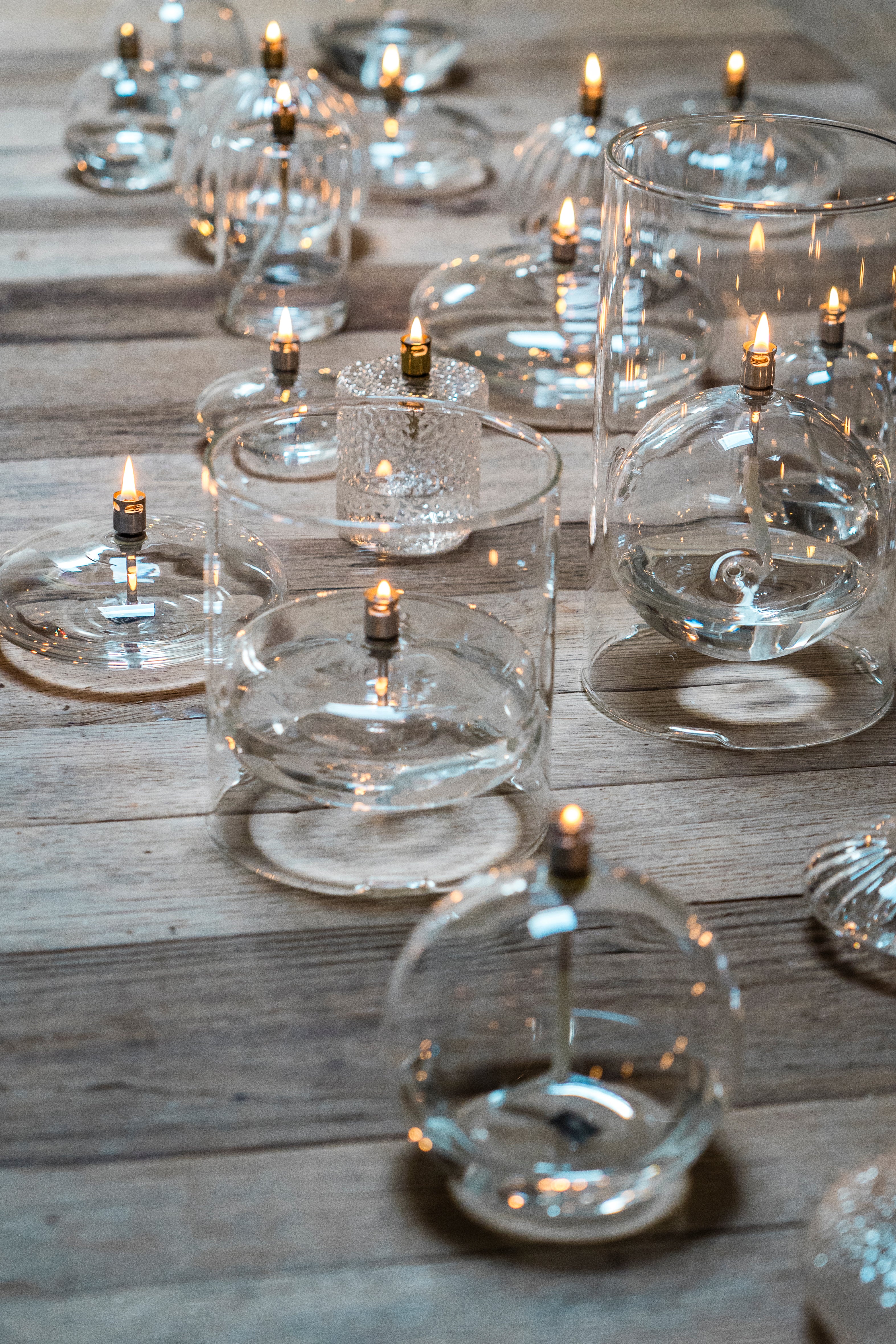 Clear glass candle holders with lit candles on a wooden surface