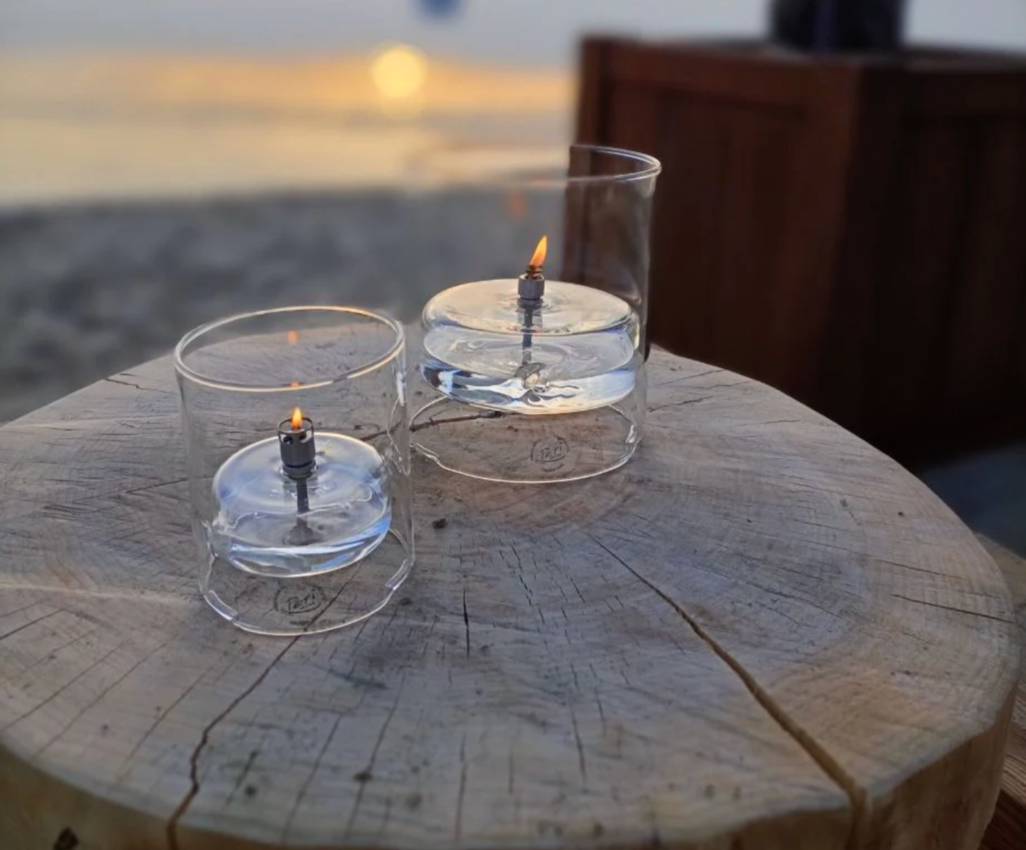 Two glass containers with flames on a wooden surface