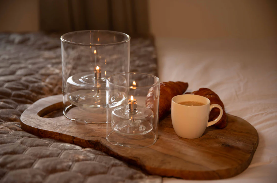 Wooden tray with candles and a cup on a bed