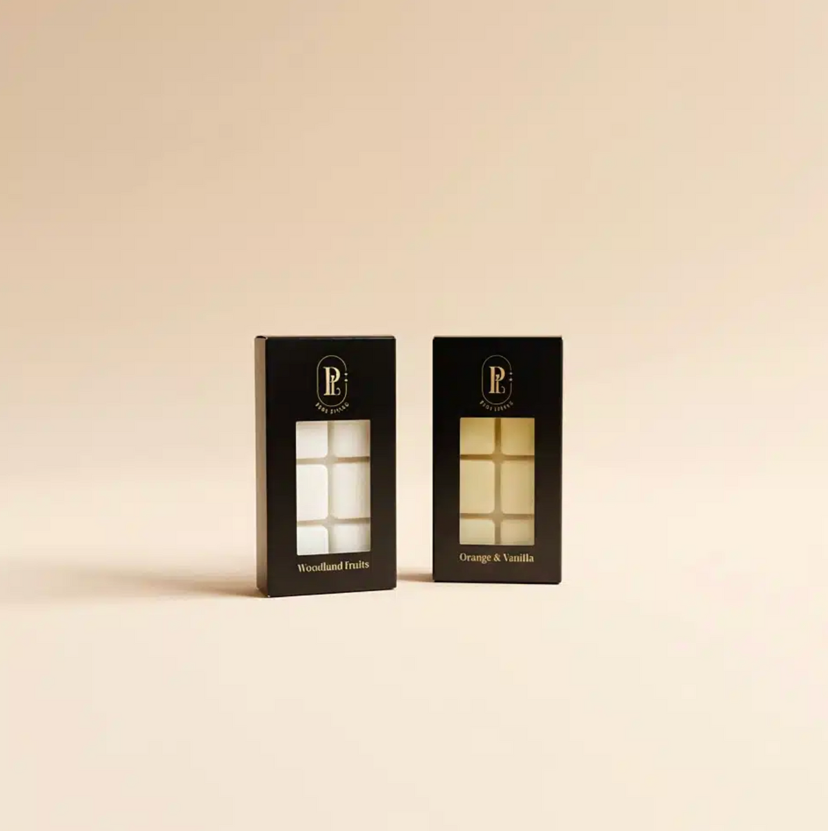 Two black boxes with windowed fronts displaying candles on a beige background