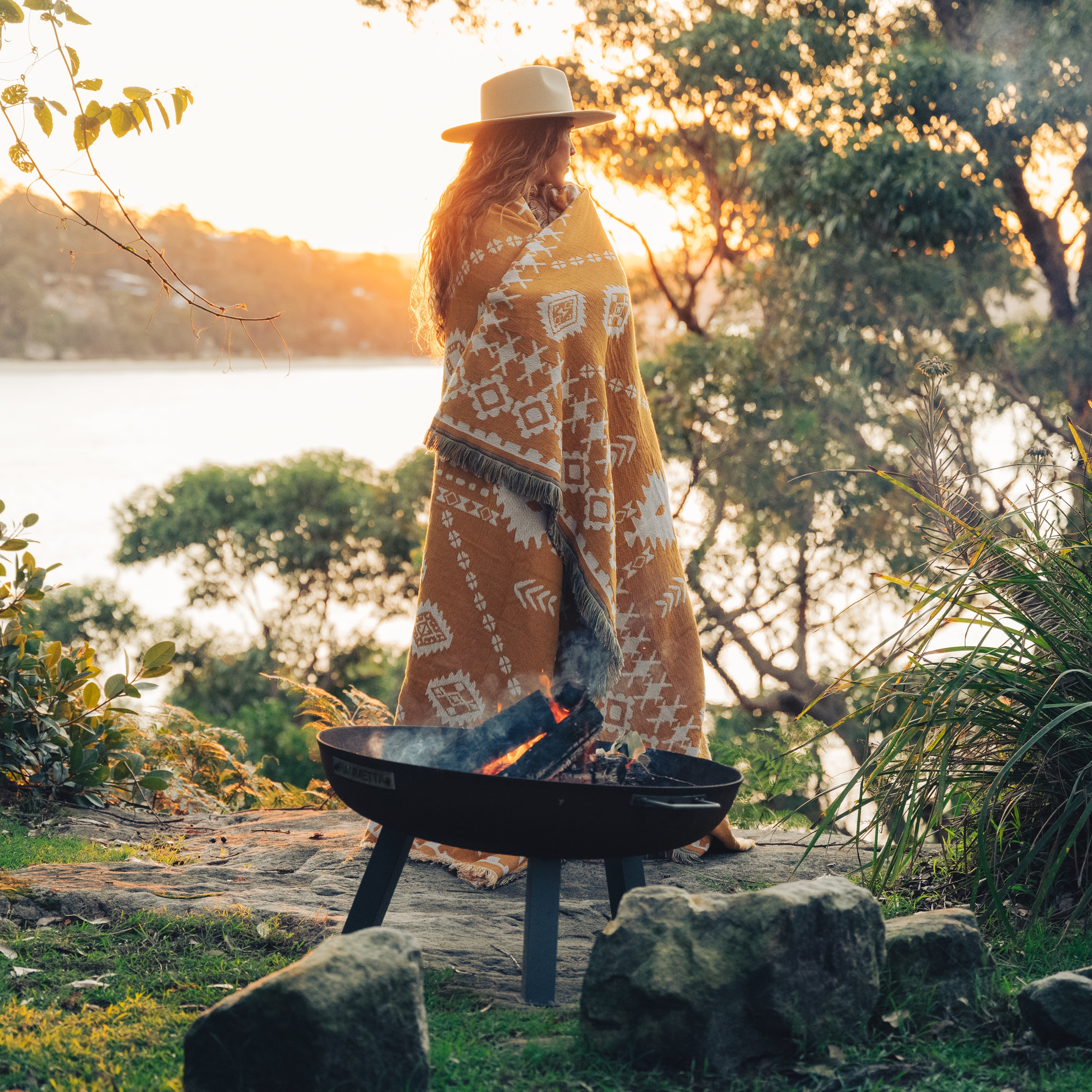 women wrapped in rug by firepit