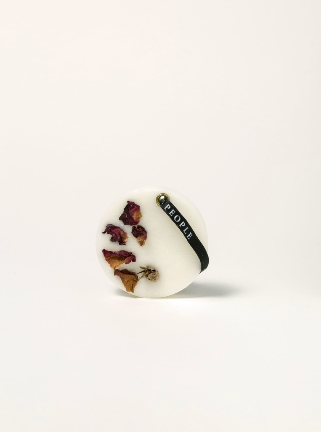 Round white object with dried flowers and a black band labeled 'People' on a white background